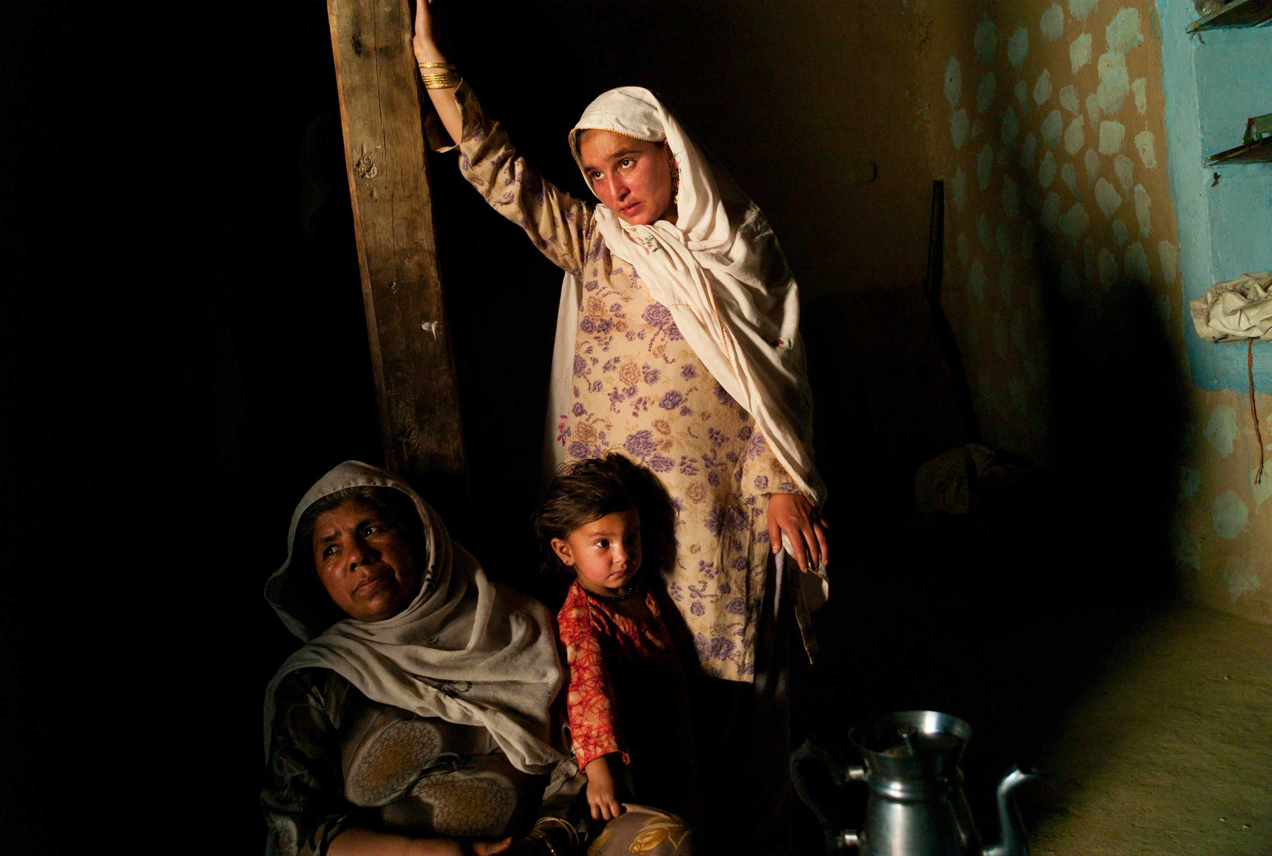 KUZA BANDAI, PAKISTAN- JUNE 2010  
                              66 year old mother of seven Gul Mina sits with her granddaughter in their small mud built home in the former Taliban stronghold of Derakai on the west bank of the Swat Valley. Along with her husband and five sons, Gul Mina, like the majority of women in her village, were ardent Taliban supporters. While her boys were ready to join the insurgents, Gul Mina became doubtful when the assassinations and beheadings began but it was hard to change sides within such a hardcore, close-knit community. As army operations commenced in the spring of 2009, she persuaded her family to flee the valley in search of refuge.