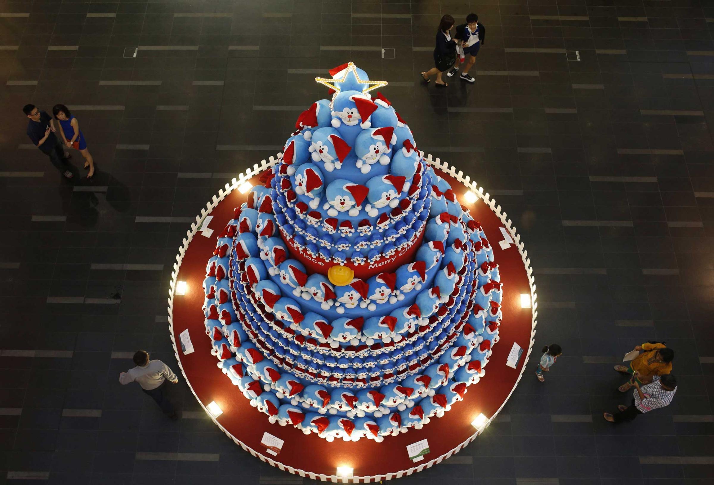 People take photos of a Christmas tree made up of Japanese Manga character Doraemon at a shopping mall in Singapore