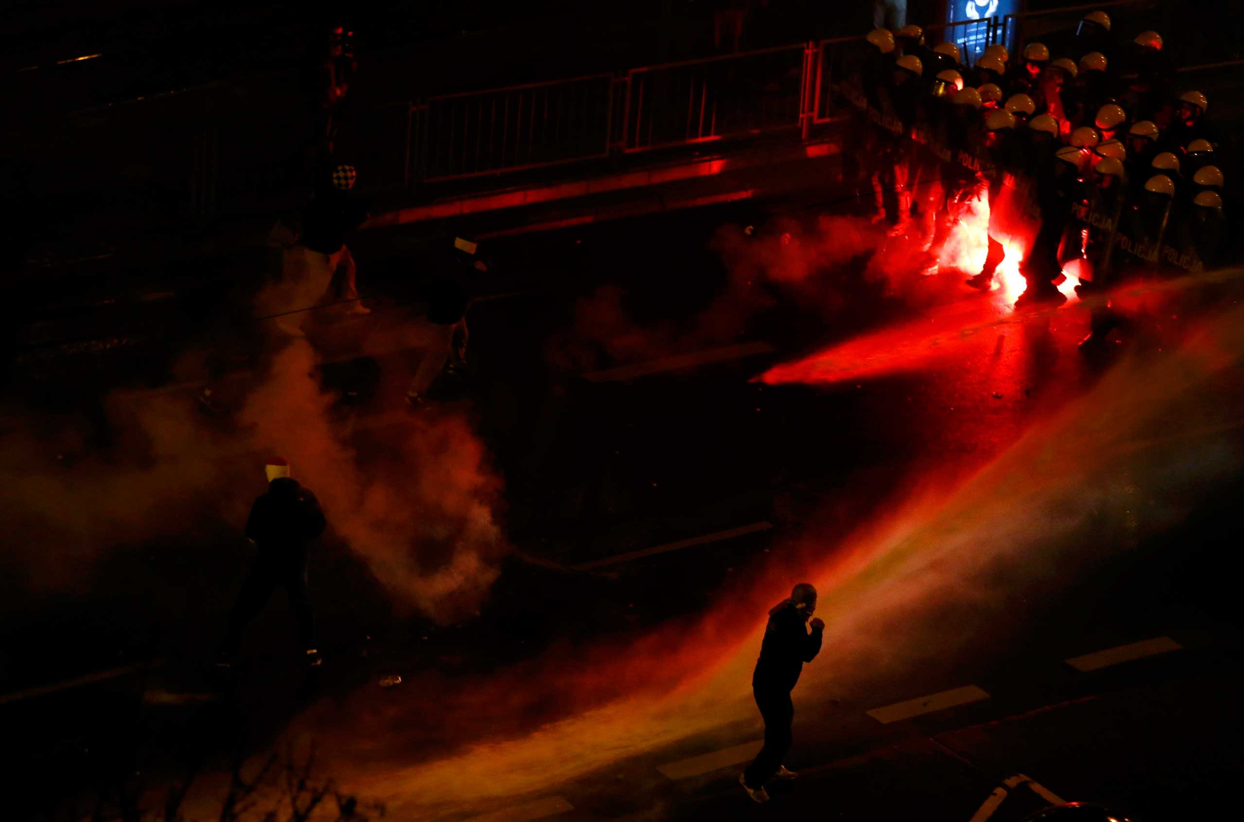 Nov. 11, 2014. Police use water cannon to push back several hundred masked men who broke away from a far-right march and threw stones and flares at lines of riot police in Warsaw.  Nationalist groups march through Warsaw each year to mark the anniversary of Polish independence, but for the fourth year in a row the procession turned violent.