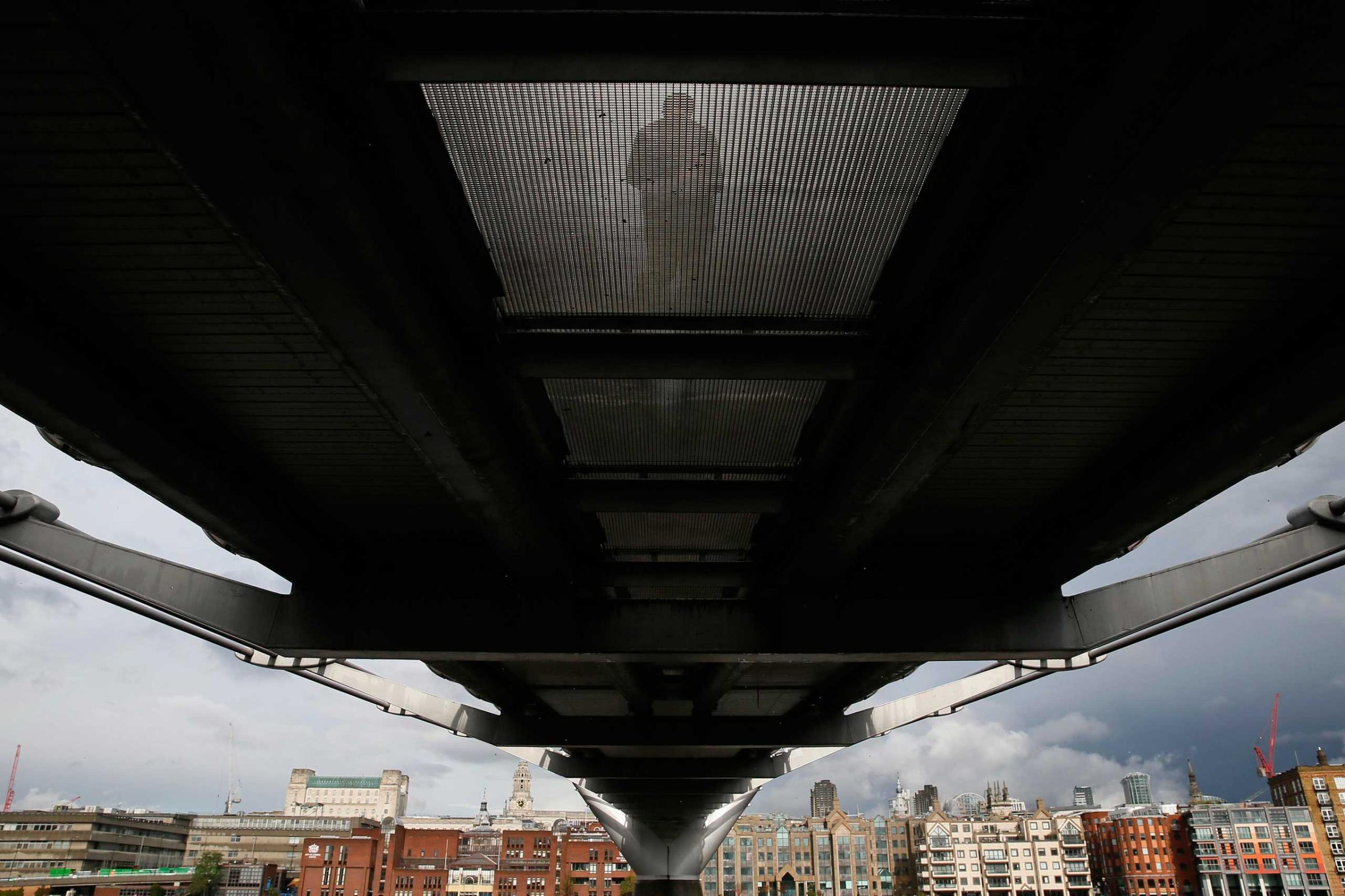 A pedestrian crosses the Millennium Bridge towards the financial district in the City of London