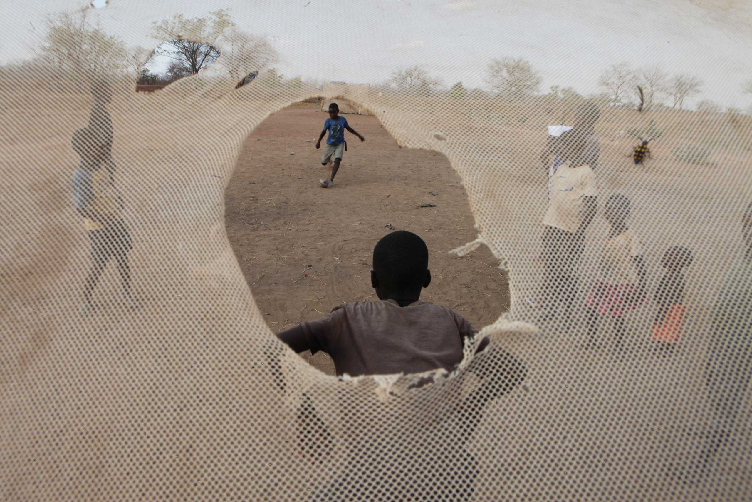 Nov, 10, 2014. Children are seen through a mosquito net used as  goal post net on the outskirts of  Lusaka, Zambia.