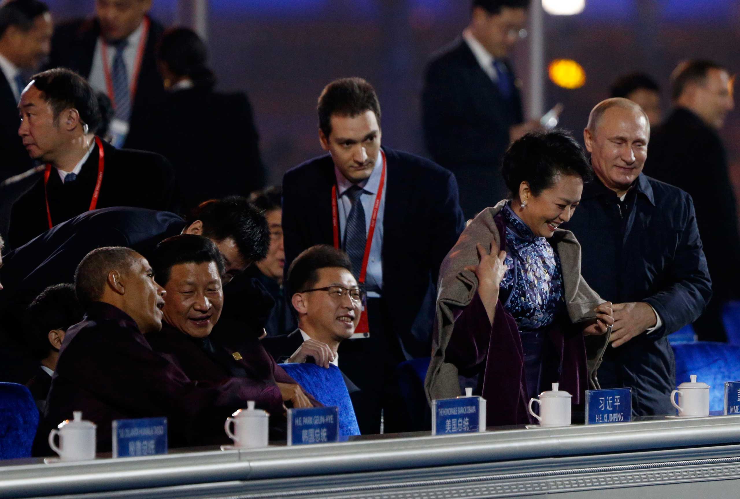 Nov. 10, 2014. Russia's President Vladimir Putin helps put a blanket on Peng Liyuan (second right), wife of China's President Xi Jinping (second left), as Xi talks to President Barack Obama during a lights and fireworks show to celebrate Asia-Pacific Economic Cooperation (APEC) Leaders' Meeting at National Aquatics Center, or Water Cube, in Beijing.