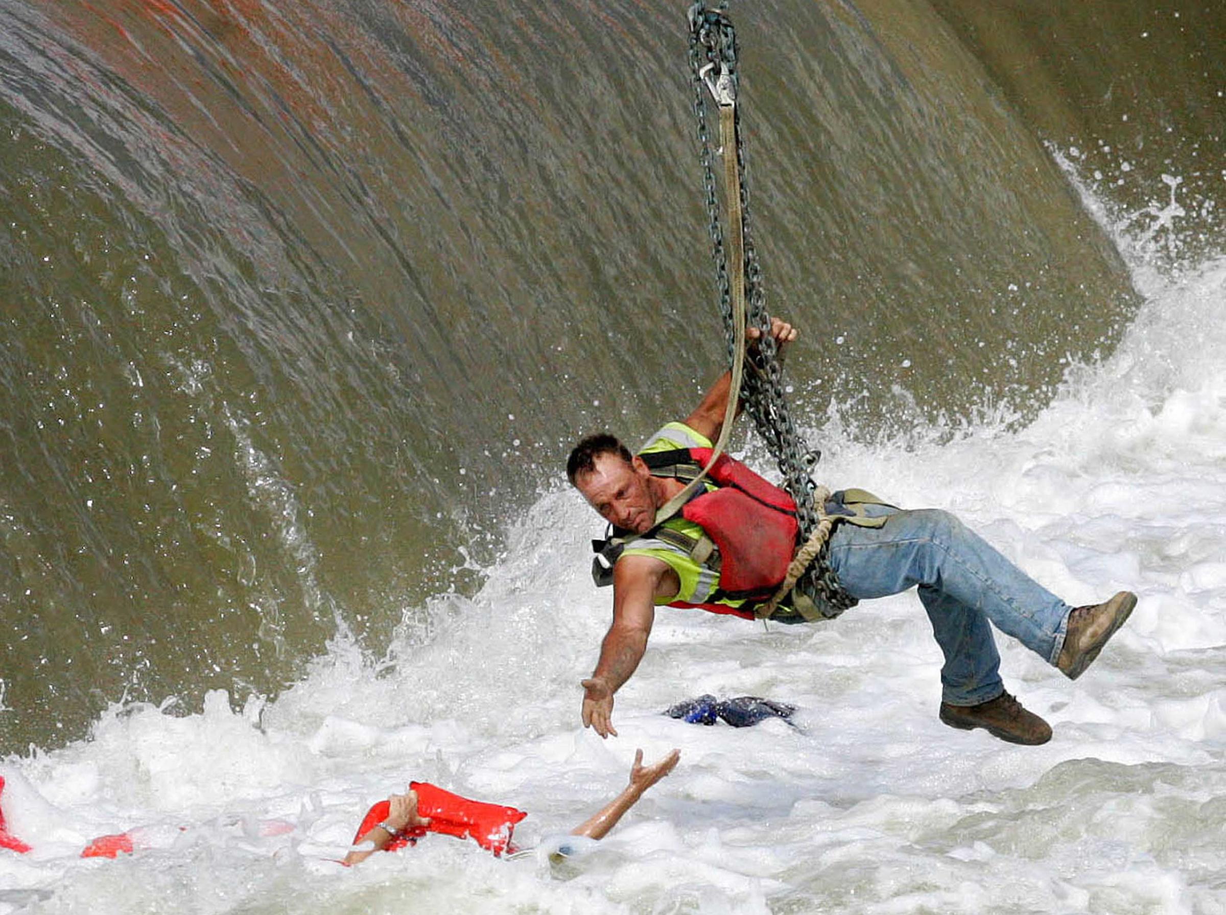 A local construction worker, suspended from a crane, rescues a woman who fell into the Des Moines River in Des Moines, Iowa on June 30, 2009.