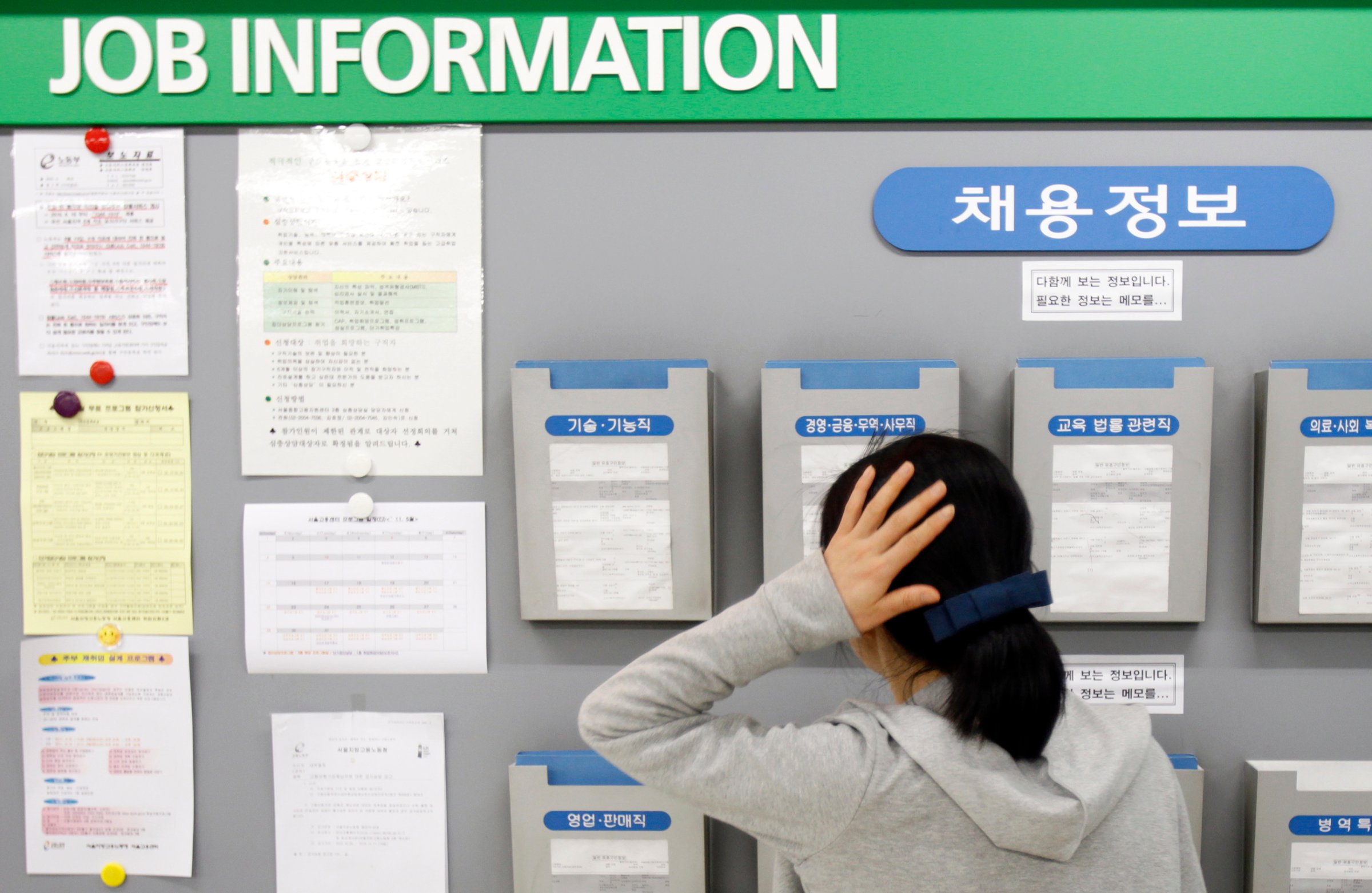 A jobseeker looks at a board showing job information at an office of the Employment Information Service in Seoul