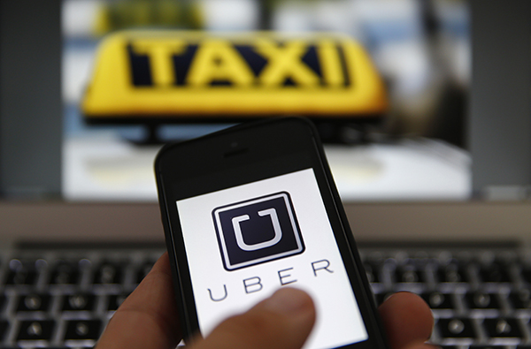 An illustration picture shows the logo of car-sharing service app Uber on a smartphone next to the picture of an official German taxi sign in Frankfurt, September 15, 2014.