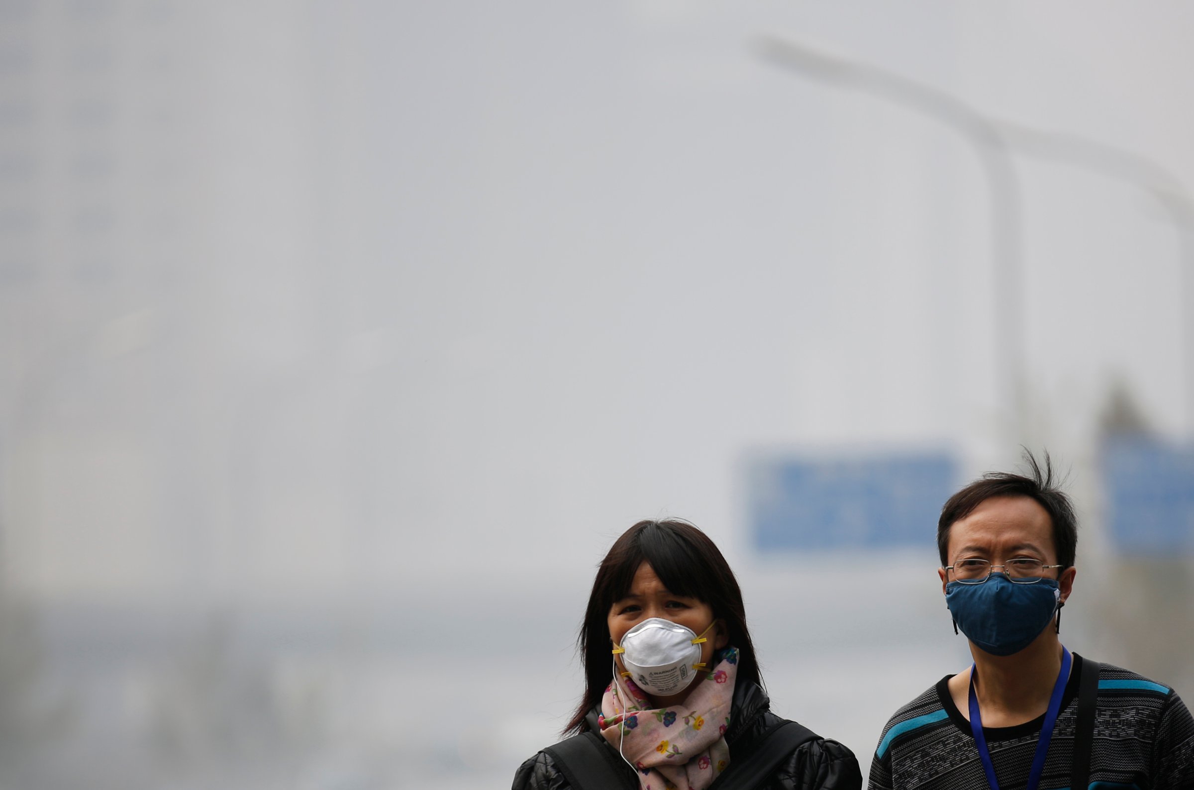 People wearing masks walk on a street amid heavy haze and smog in Beijing