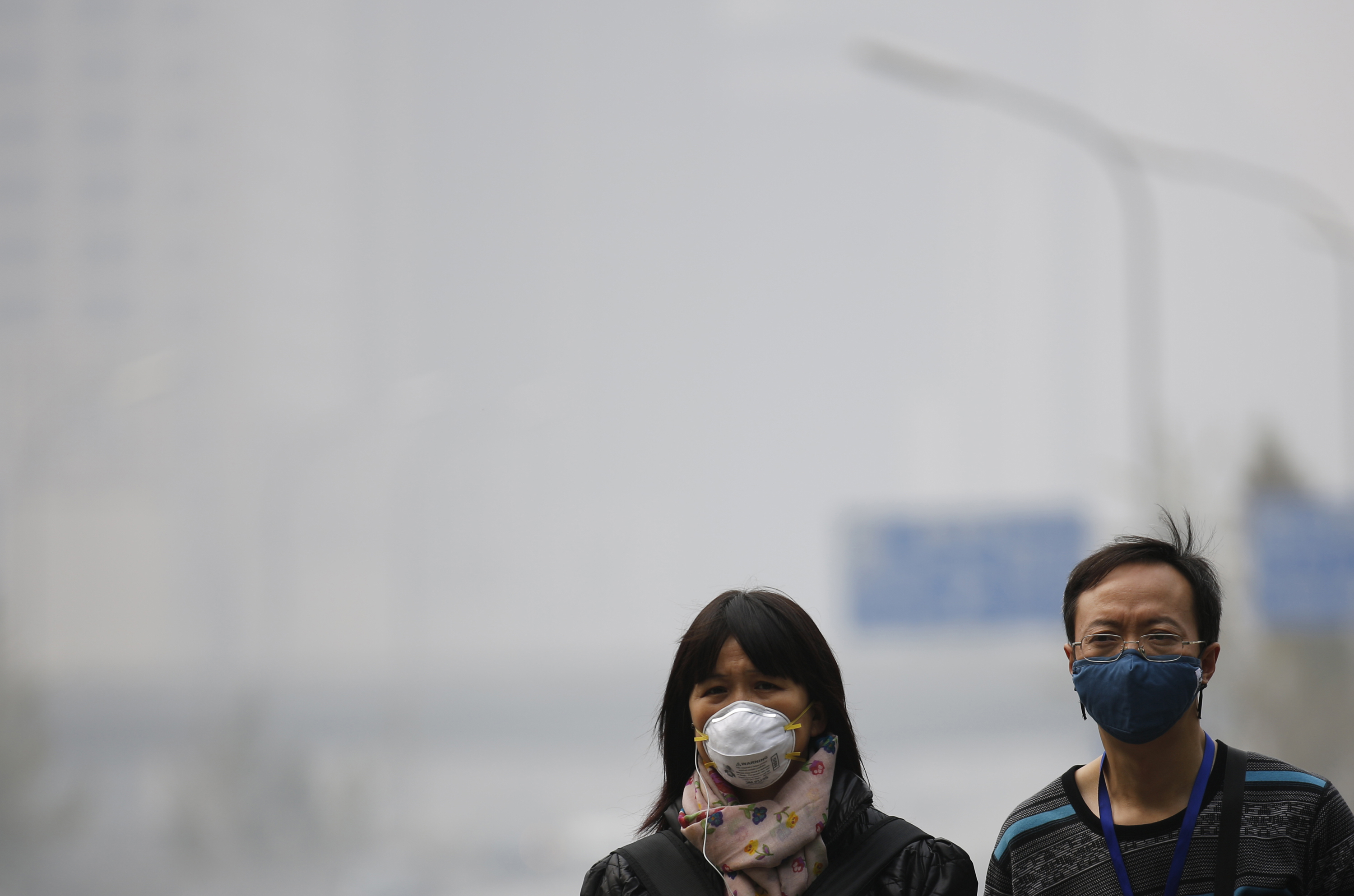 People wearing masks walk on a street amid heavy haze and smog in Beijing