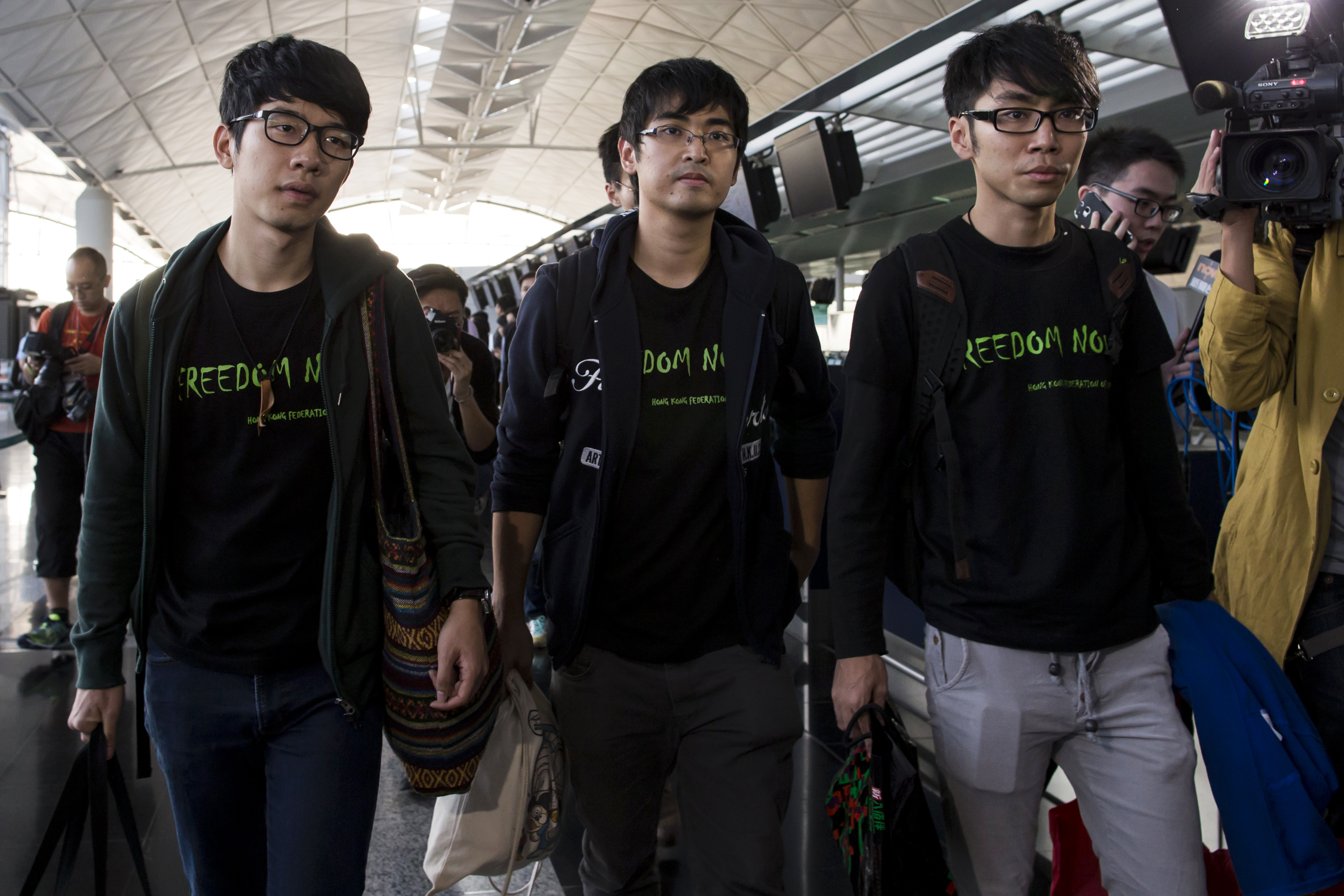 Hong Kong Federation of Students leader Alex Chow, committee members Nathan Law and Eason Chung react after being refused to board the plane at the Hong Kong International Airport