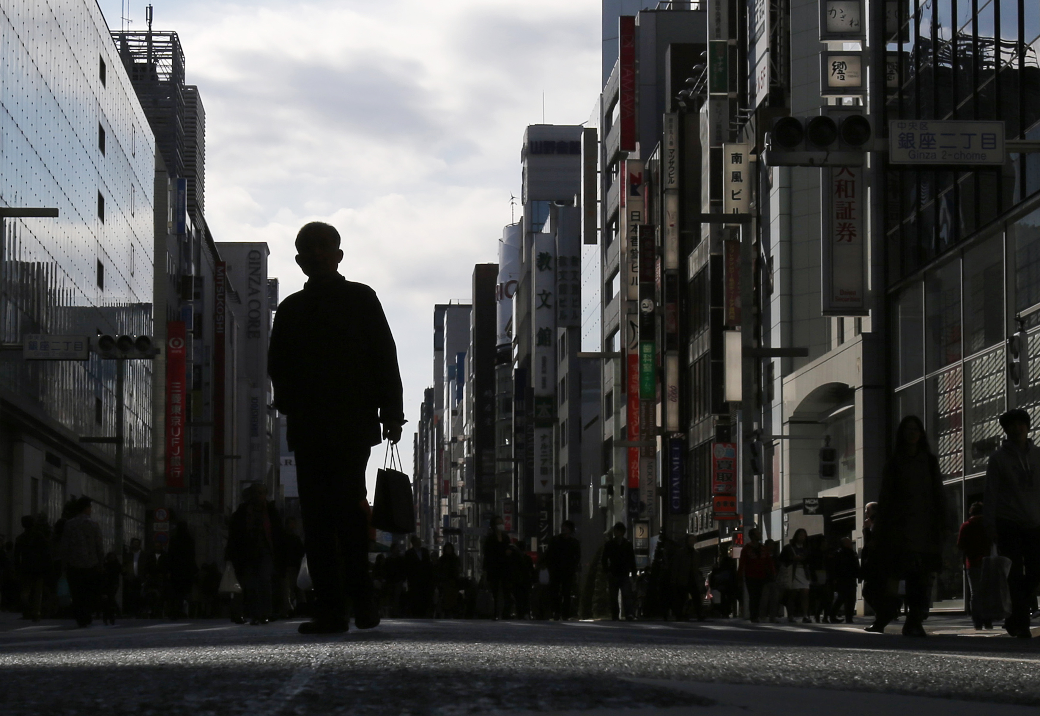 A man holding a shopping bag walks on a street at Tokyo's Ginza shopping district