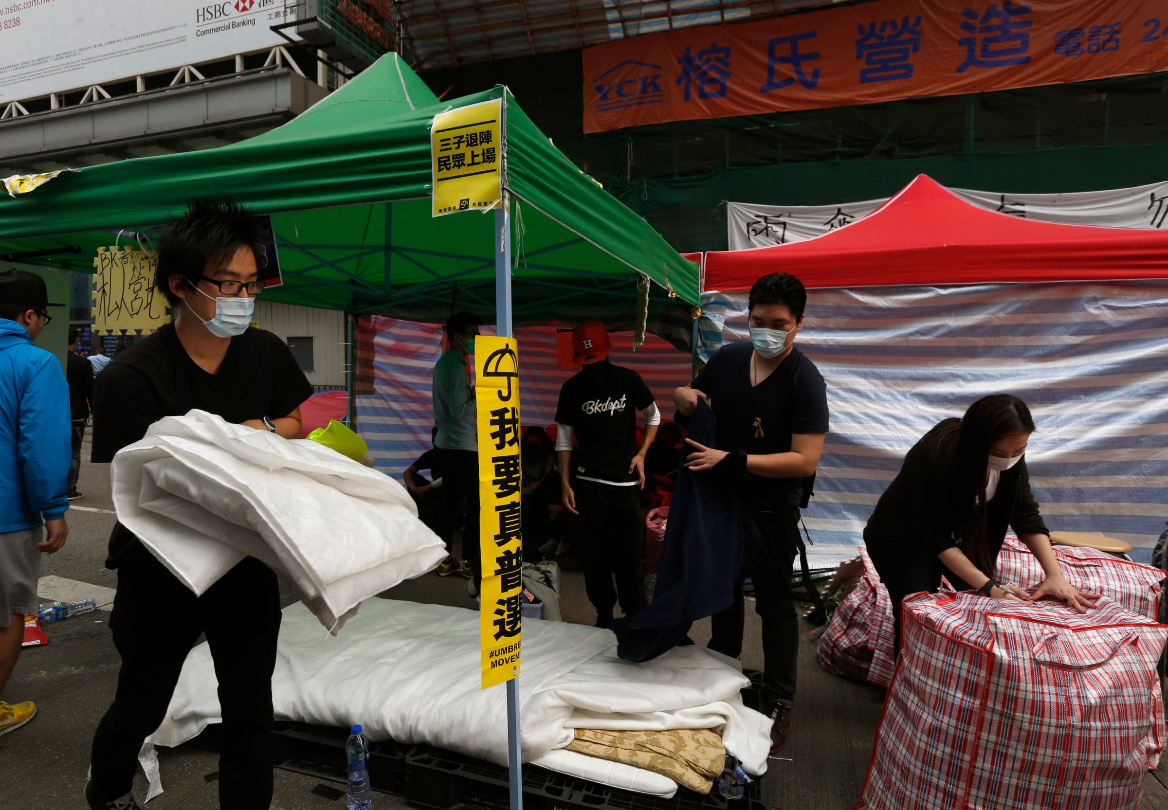 Masked pro-democracy protesters pack their belongings, before they are removed by bailiffs under a court injunction, at Mong Kok shopping district in Hong Kong
