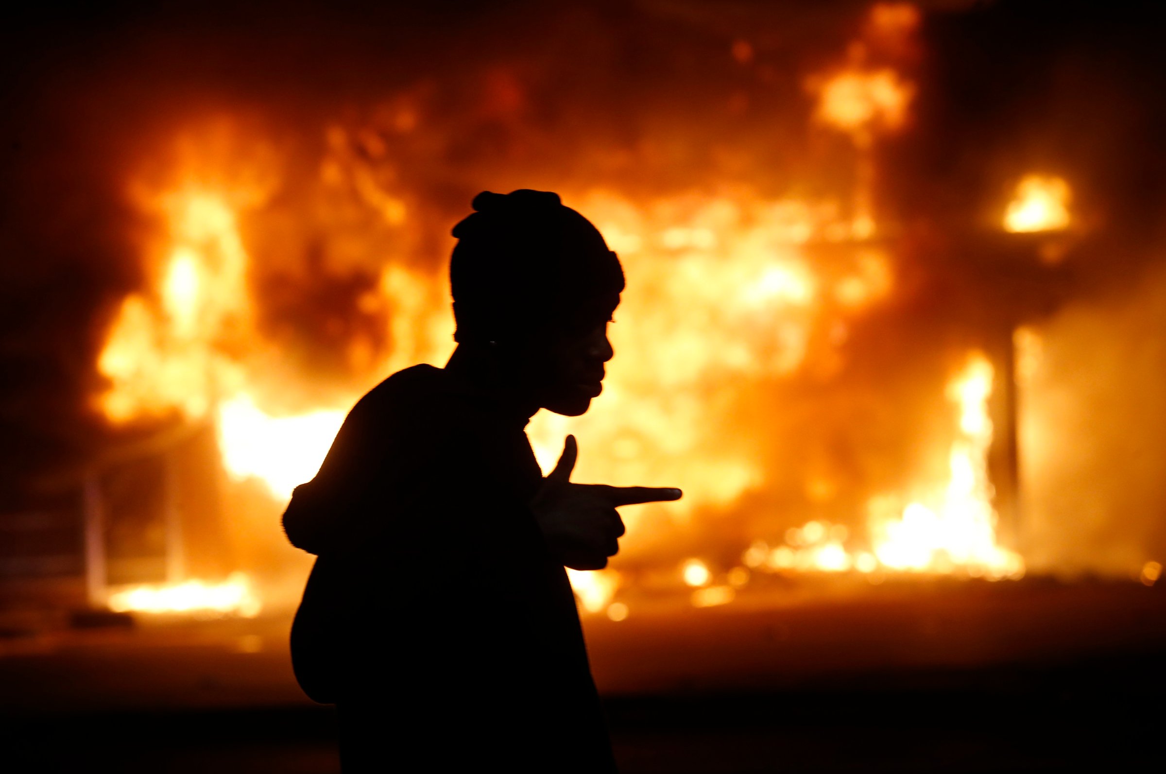 A man walks past a burning building during rioting after a grand jury returned no indictment in the shooting of Michael Brown in Ferguson, Missouri