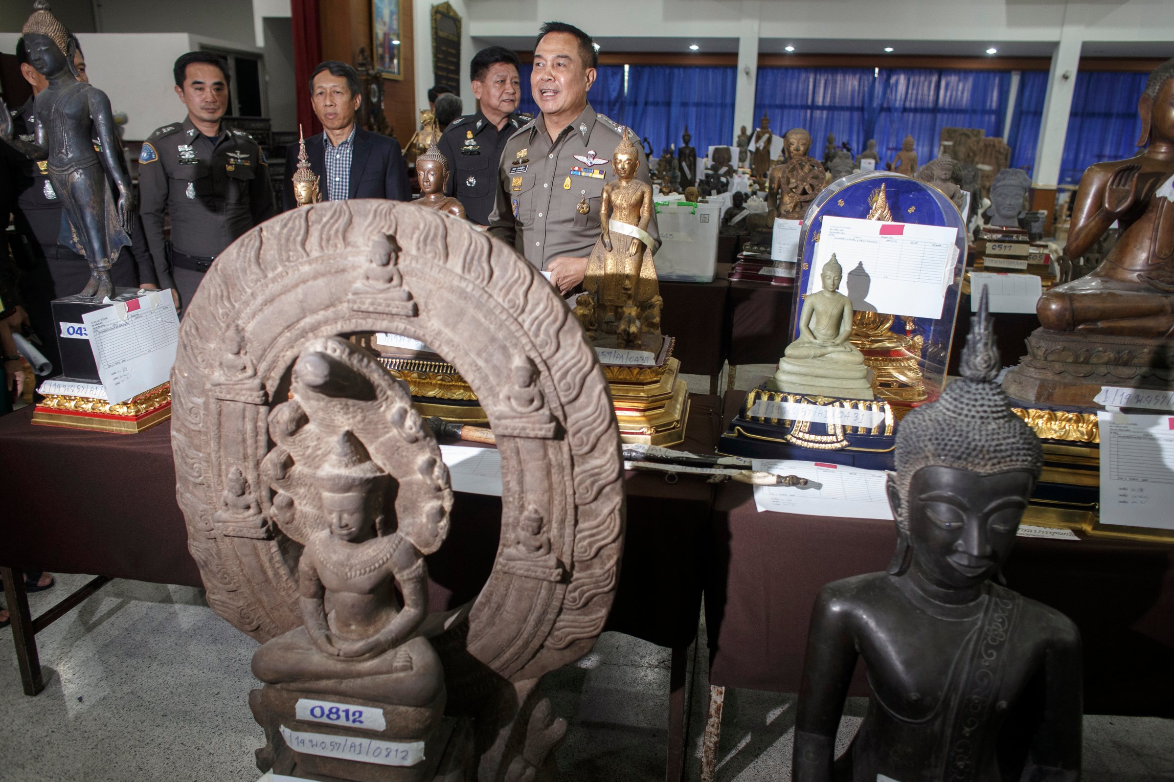 Poompanmuang, chief of Royal Thai Police, stands among antique Buddha statues that were seized during an investigation into Chayaphan, a former commissioner of the Central Investigation Bureau, at a military base in Bangkok