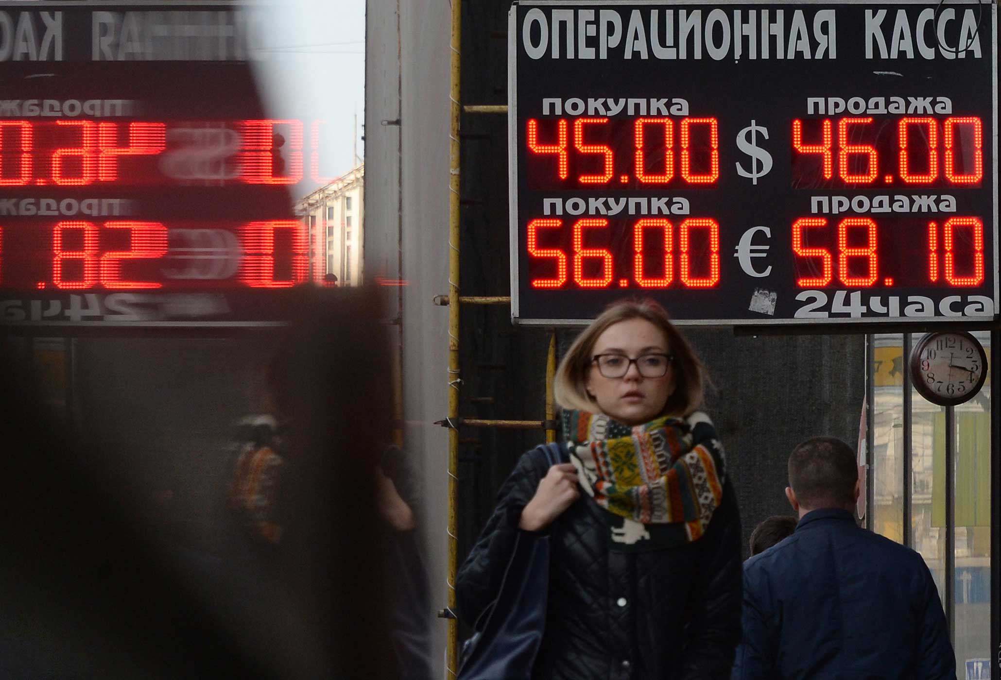 Pedestrians walk under a board listing foreign currency rates against the Russian ruble outside an exchange office in central Moscow on November 10, 2014. (Vasily Maximov—AFP/Getty Images)