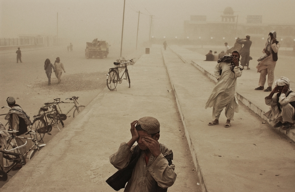 Afghanistan. Kandahar. March 2005. A boy covers his eyes during a sandstorm in the southern city of Kandahar.