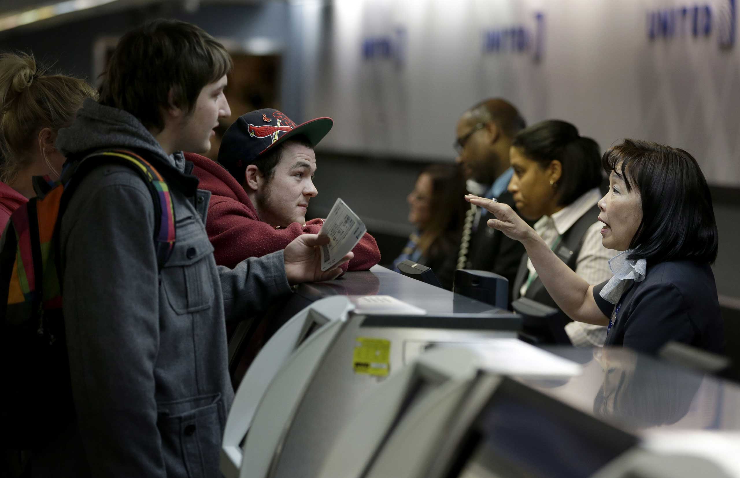 Brandon Bybee, left, and Cory McKenrick, second from left, talk with a ticket agent to try and move up their flight to Illinois in order to beat an expected snow storm at LaGuardia Airport in New York City on Jan. 26, 2015. (Seth Wenig—AP)