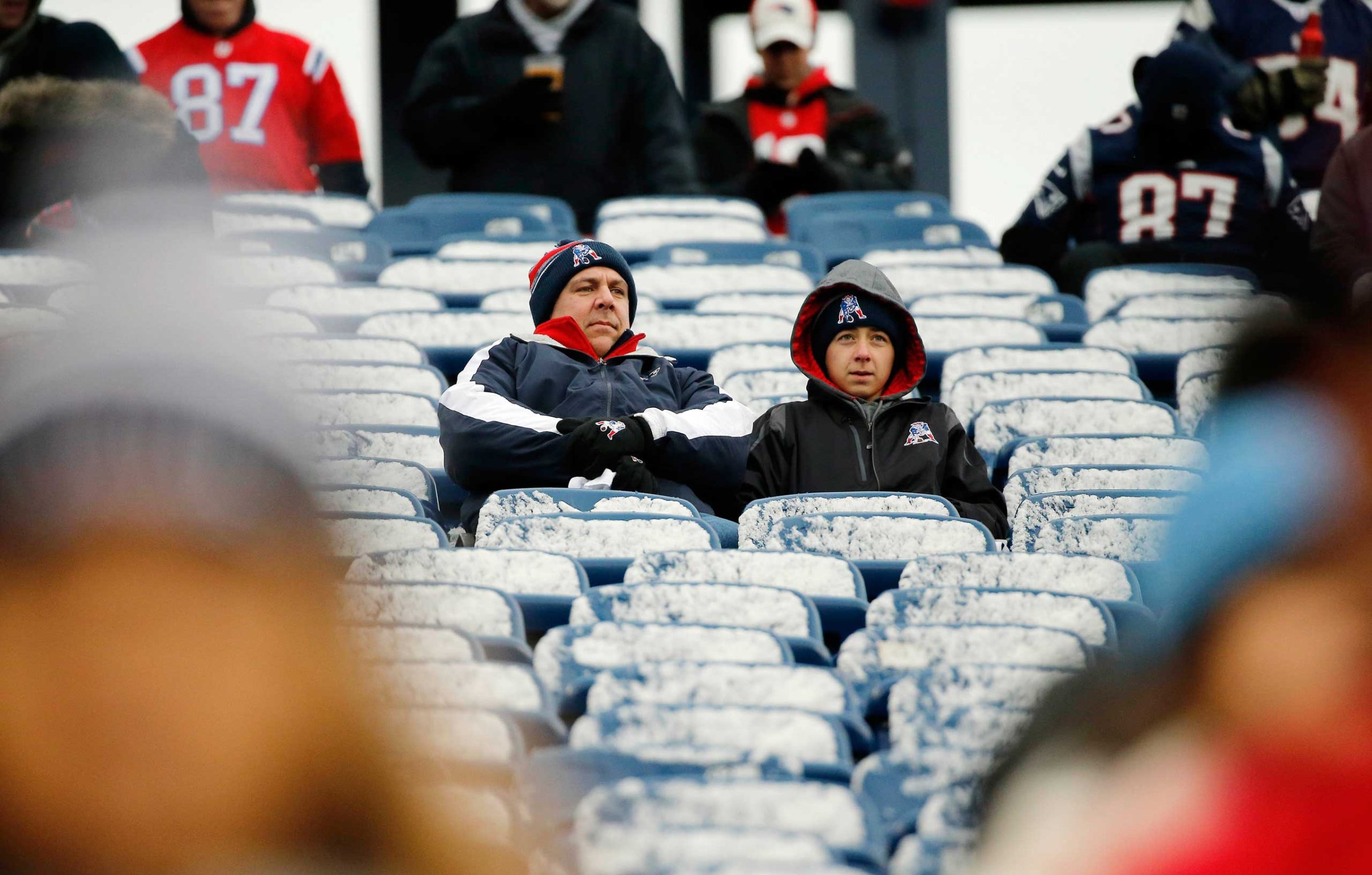New England Patriots fans sit in seats coated by a light morning snow before an NFL football game between the Patriots and the Denver Broncos on Nov. 2, 2014, at Gillette Stadium in Foxborough, Mass.