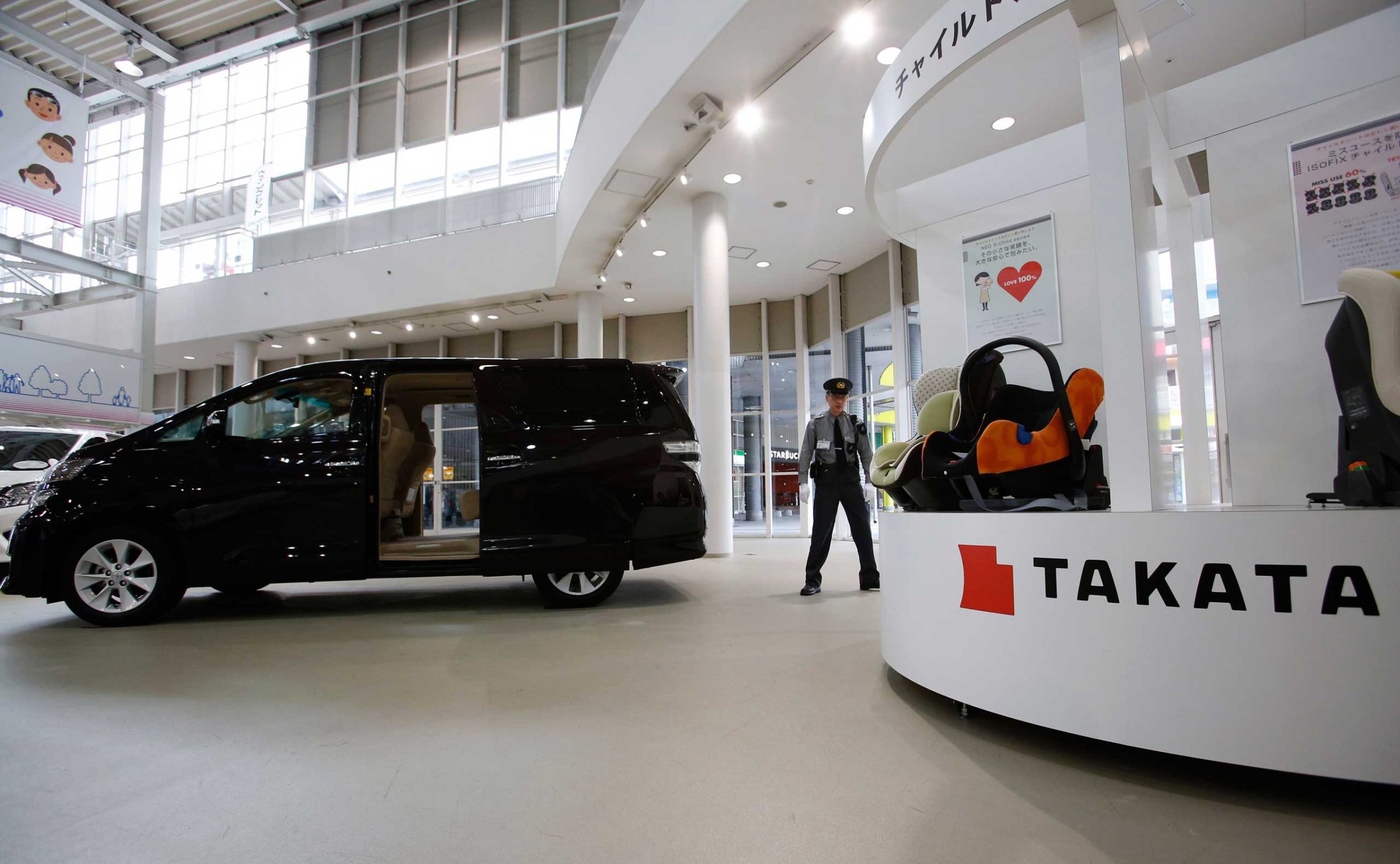 A security guard stands by child seats, manufactured and displayed by Takata Corp. at a Toyota showroom in Tokyo, Nov. 6, 2014.
