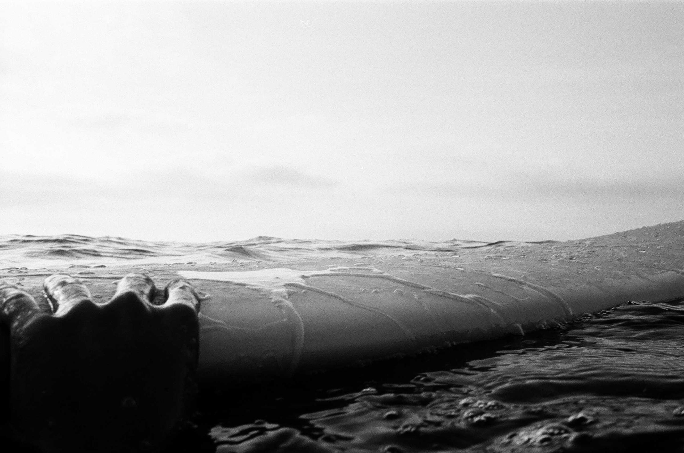 Mar Cubillos holds on to a surfboard by Rockaway beach, N.Y. in Aug. 2014