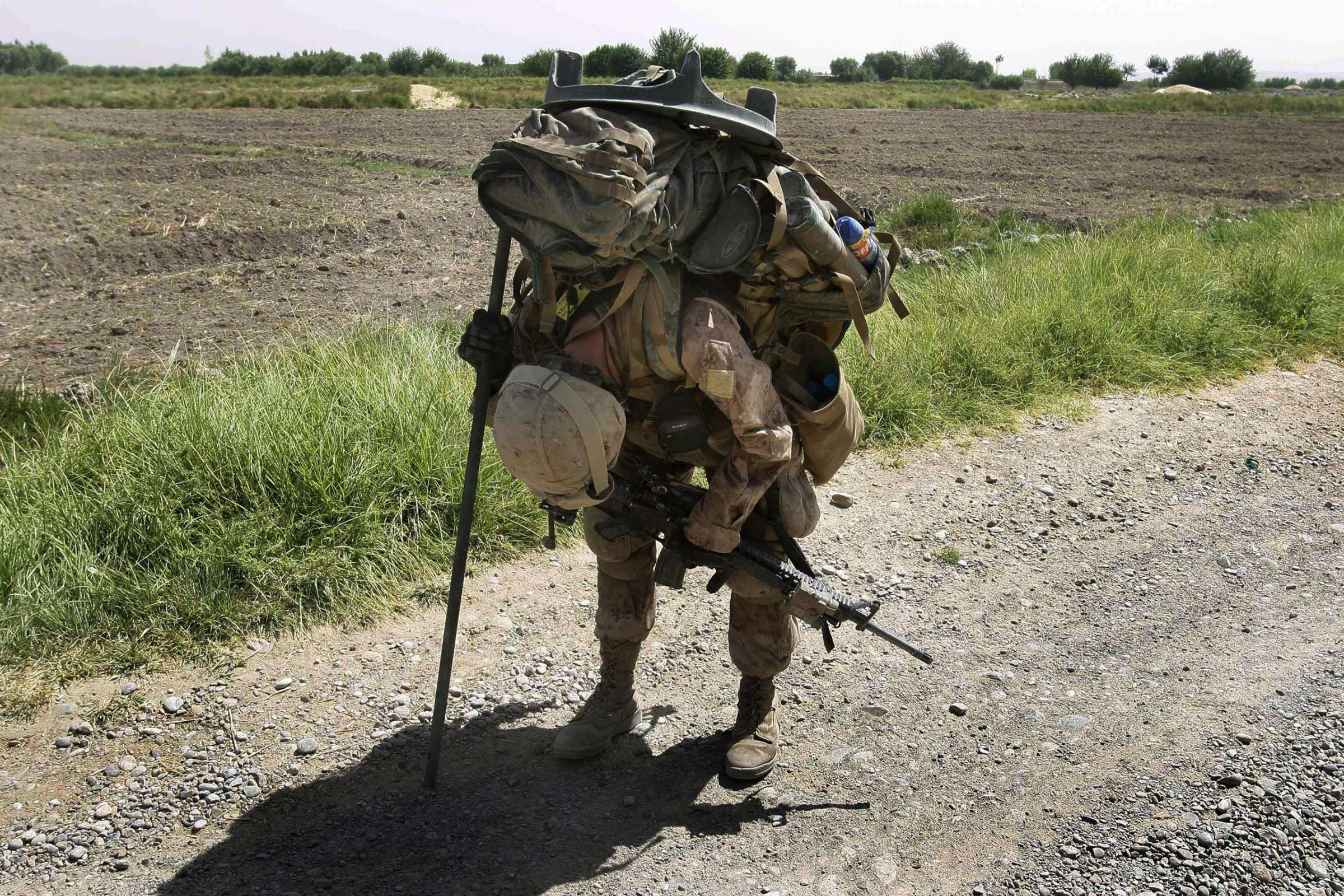 U.S. Marine Cpl. Brian Knight, of Cincinnati, Ohio, with the 2nd Marine Expeditionary Brigade, 1st Battalion 5th Marines, pauses briefly in the heat to rest with his heavy pack filled with mortar equipment, ammunition, food, and water in the Nawa district in Afghanistan's Helmand province Saturday, July 4, 2009.