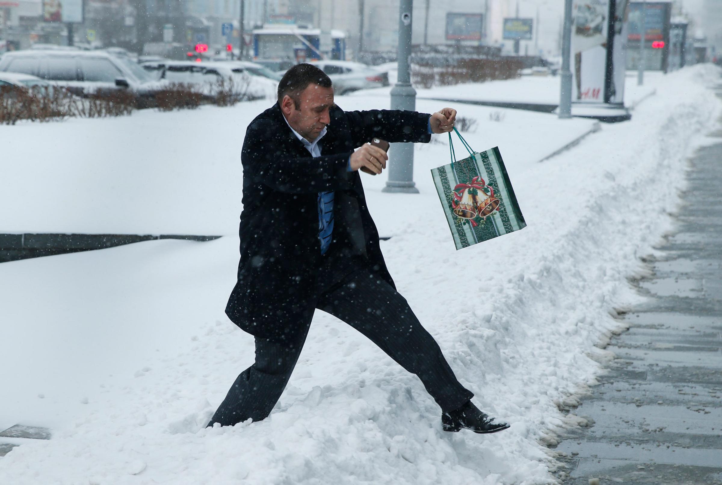 A man with a Christmas gift walks across snow during heavy snowfall in downtown Moscow on Dec. 25, 2014.