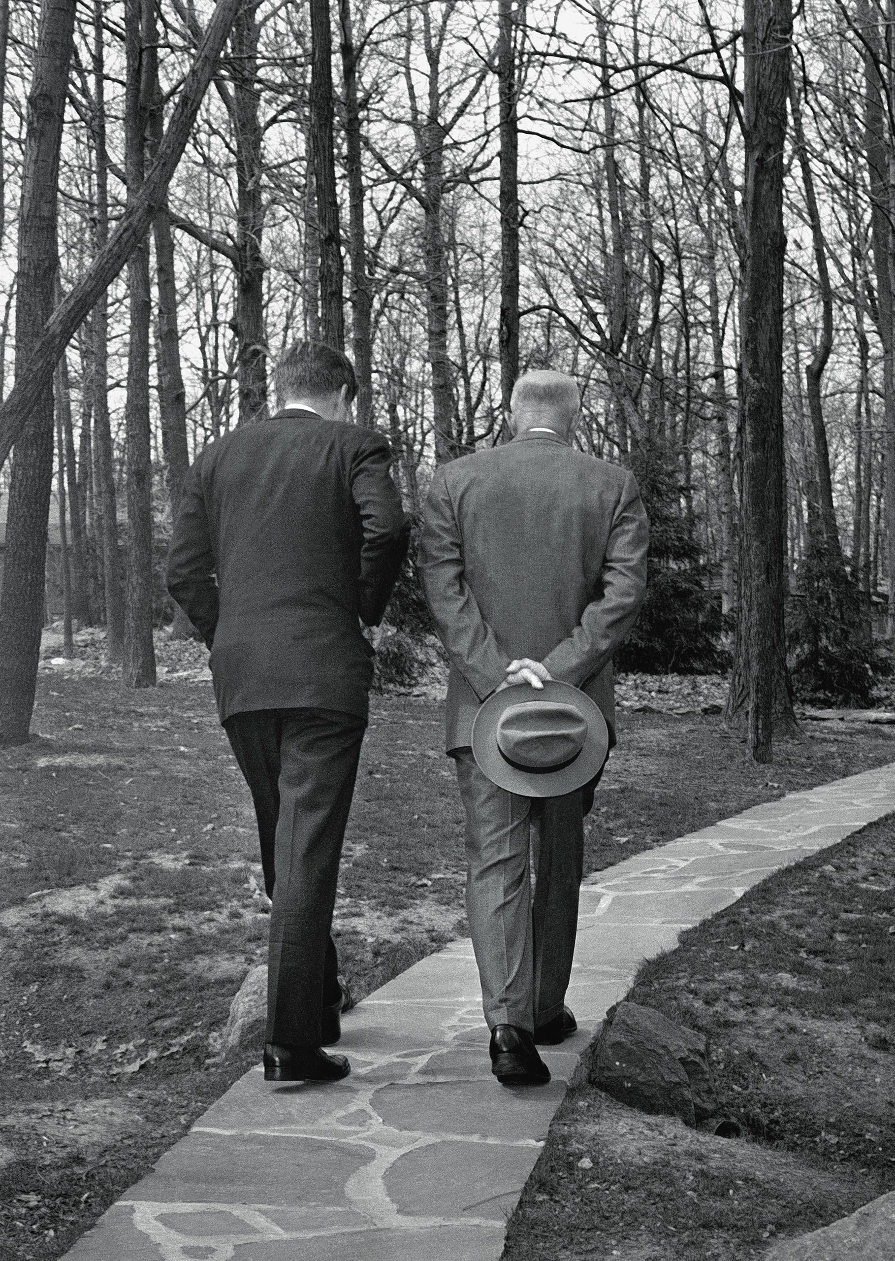 With their heads bowed, President John F. Kennedy, left, walks along a path at Camp David near Thurmont, Md., with former President Dwight D. Eisenhower on April 22, 1961, as the two met to discuss the Bay of Pigs invasion.