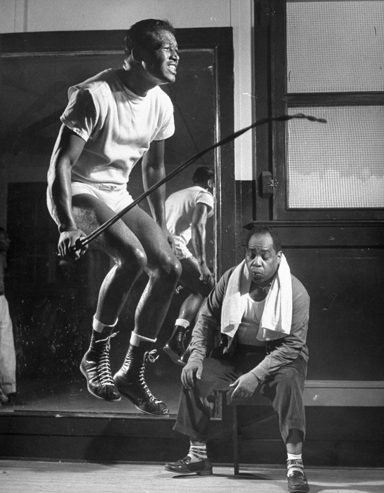 Boxer Sugar Ray Robinson skips rope to music as a routine in his training camp, 1950.