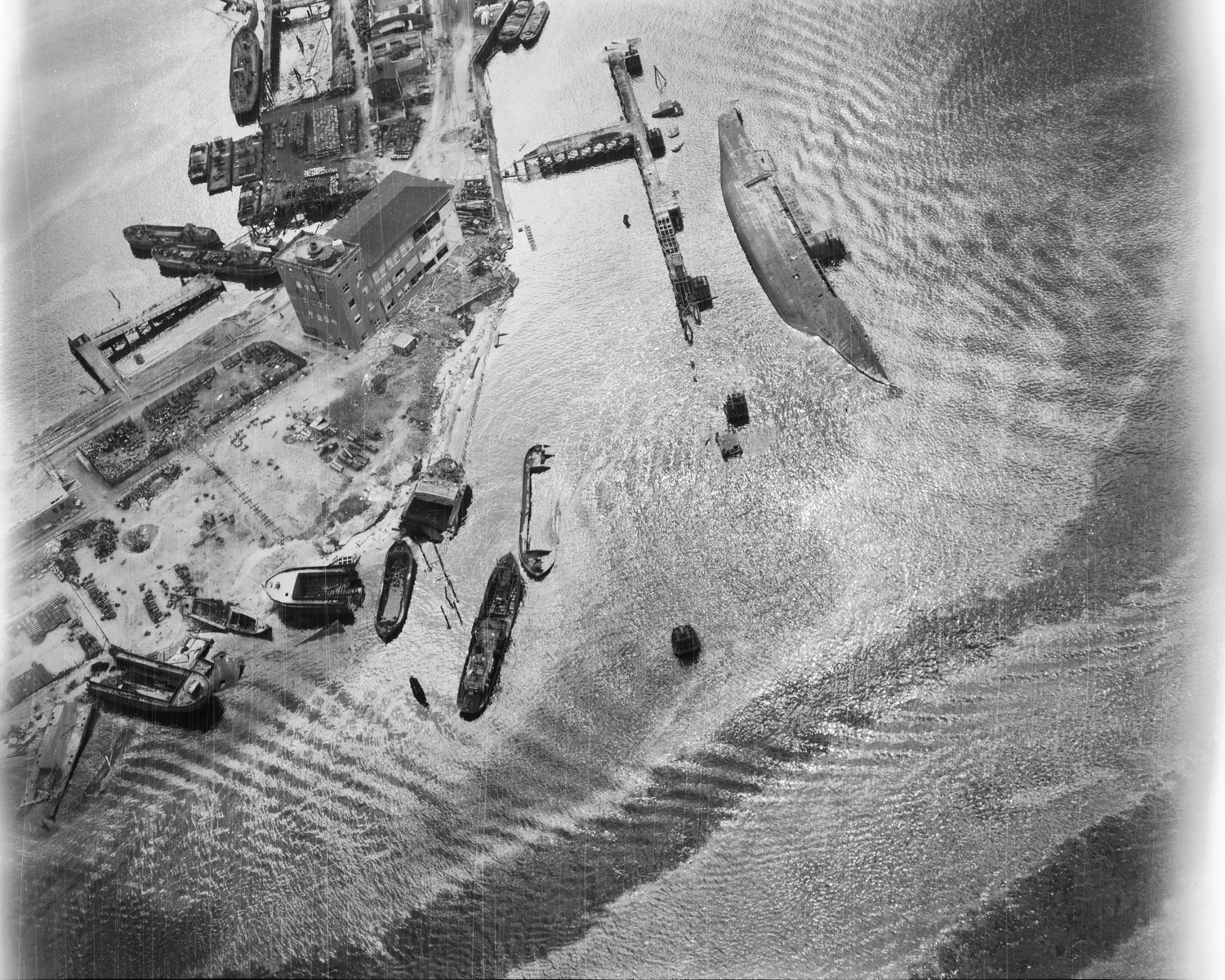Aerial view of sunken ship and bombed-out shipbuilding installation after Allied air attack on Germany's chief naval base at Kiel, near Baltic harbor.