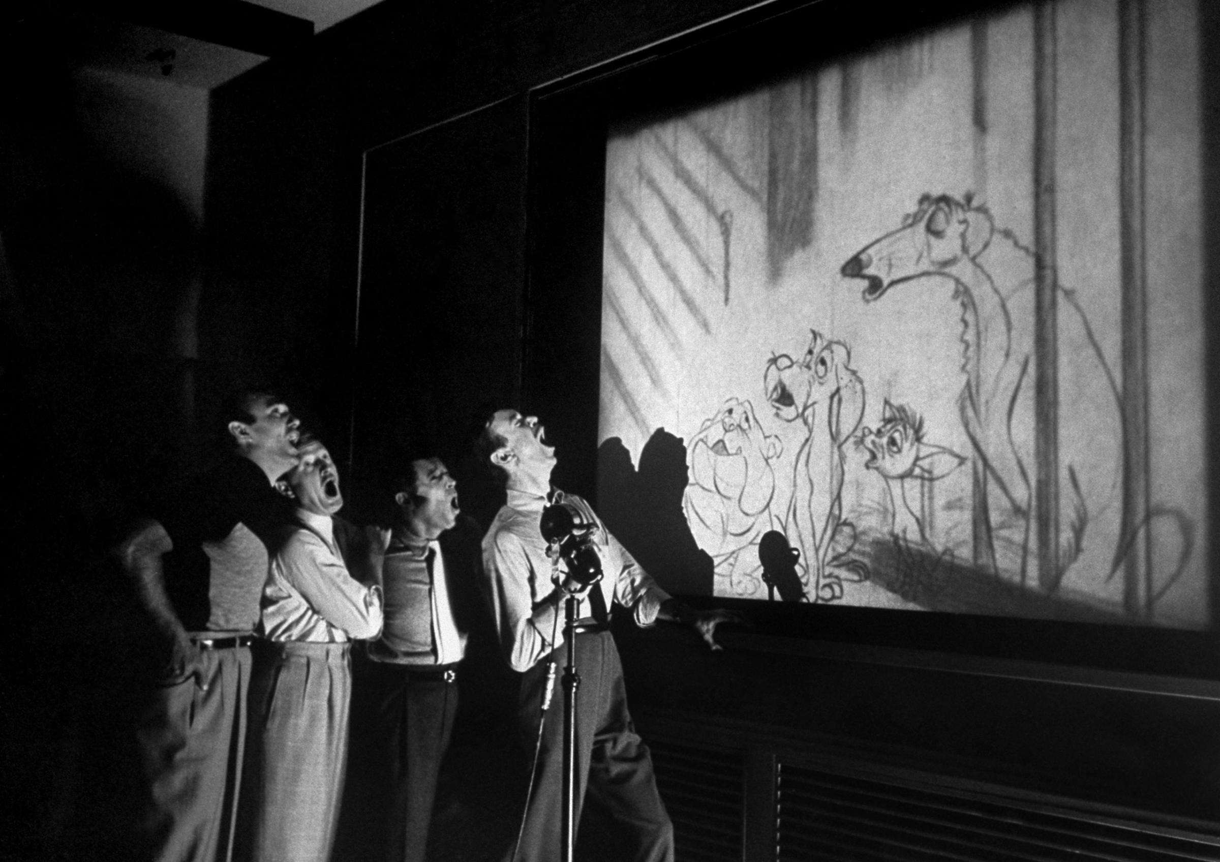 Quartet known as The Mello-Men bays in harmony before screen showing four canine characters whose voices they represent in the forthcoming Disney feature cartoon, The Lady and The Tramp.