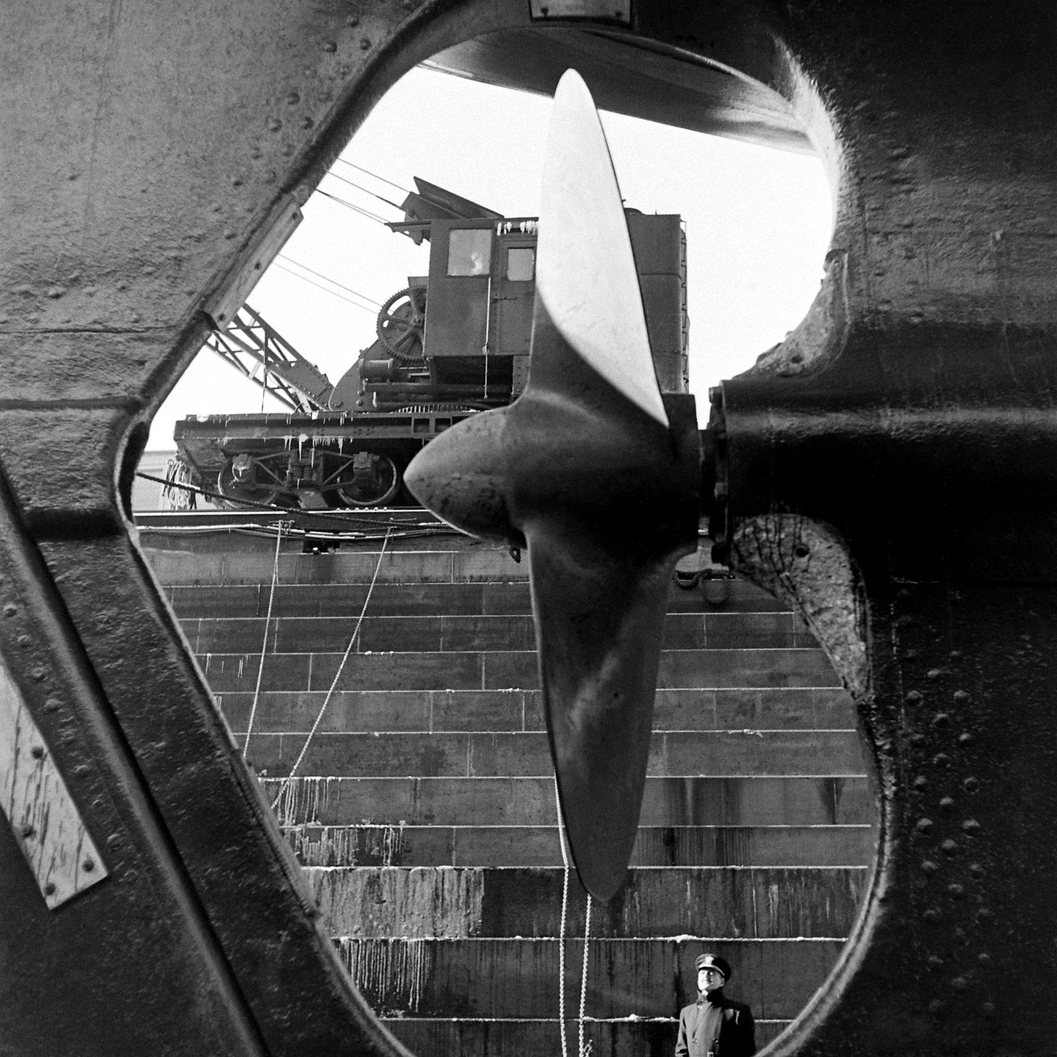 A Naval officer gazes at a cruiser's propeller at the Brooklyn Navy Yard.
