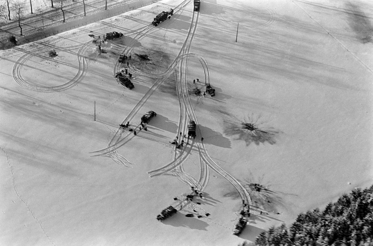 American trucks and half-tracks in a snow-covered Ardennes field, Battle of the Bulge.