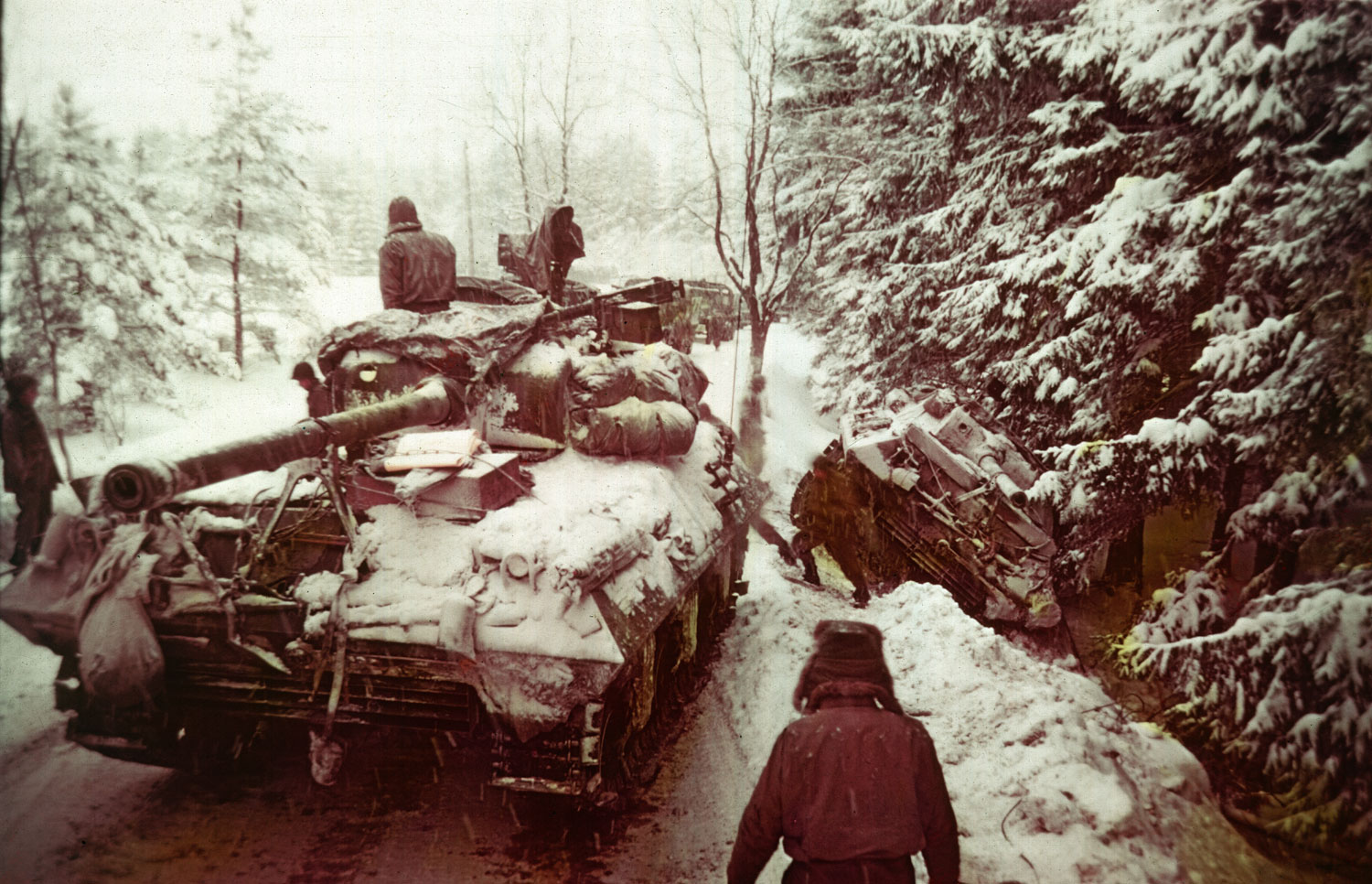 An American tank moves past another gun carriage which slid off an icy road in the Ardennes Forest during the Battle of the Bulge, Dec. 20, 1944.