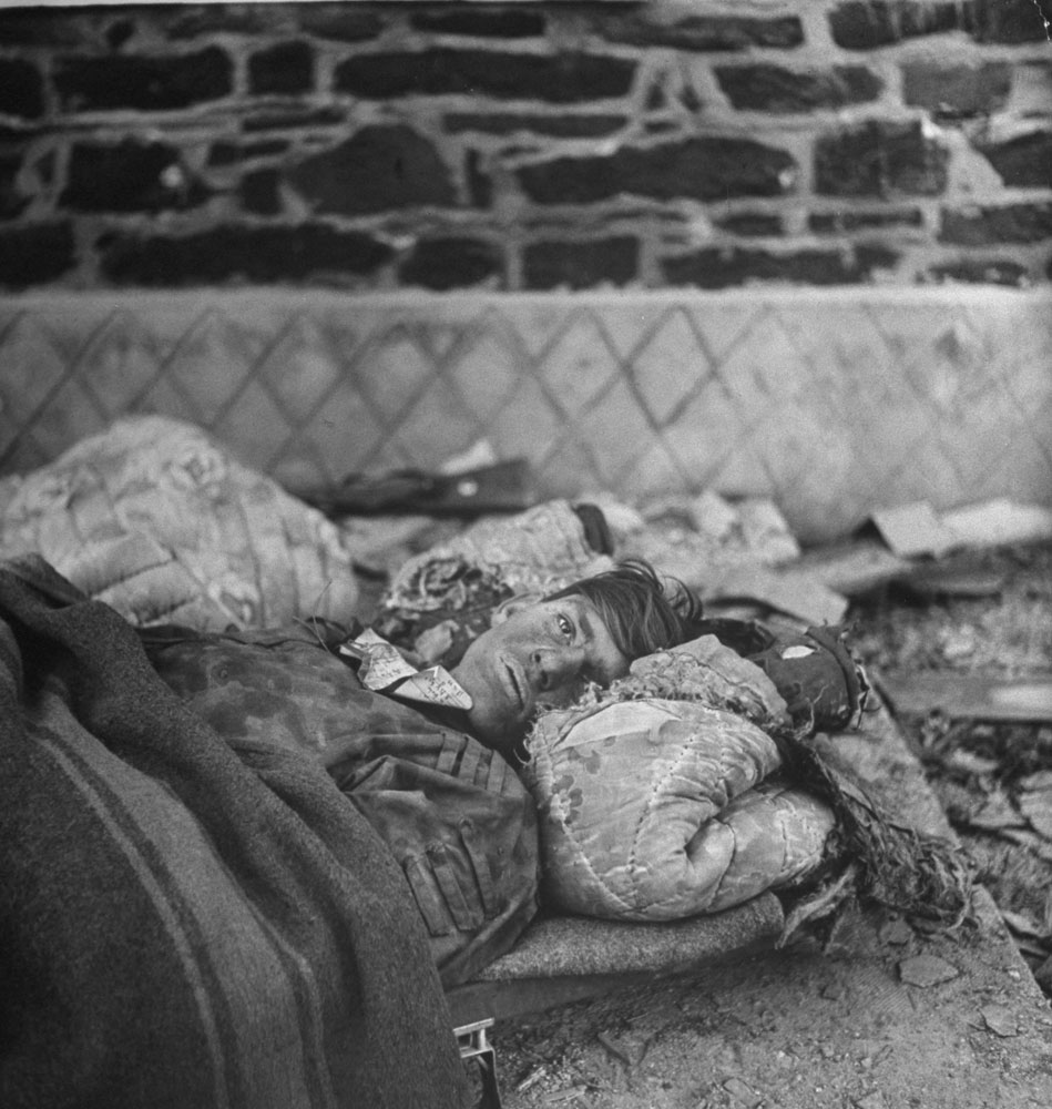 A wounded German soldier rests on makeshift bedding after being taken prisoner during an attack on an American fuel depot on Dec. 16, 1944, the first day of the Battle of the Bulge.