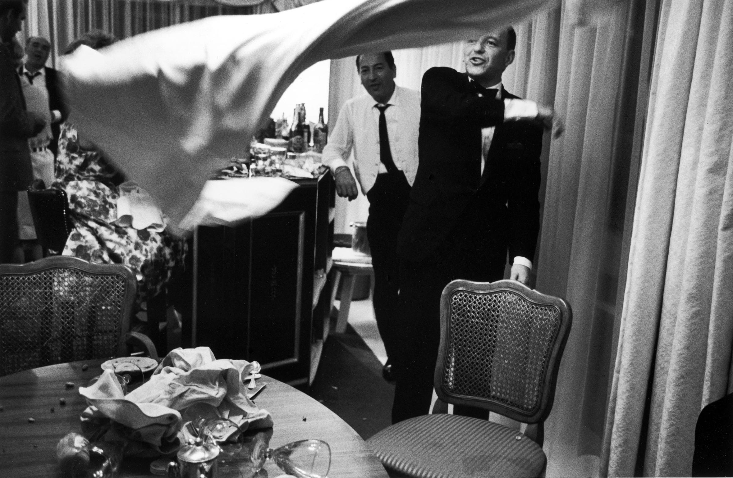In Miami in 1965, Frank Sinatra tosses a tablecloth after yanking it from a cluttered tabletop.