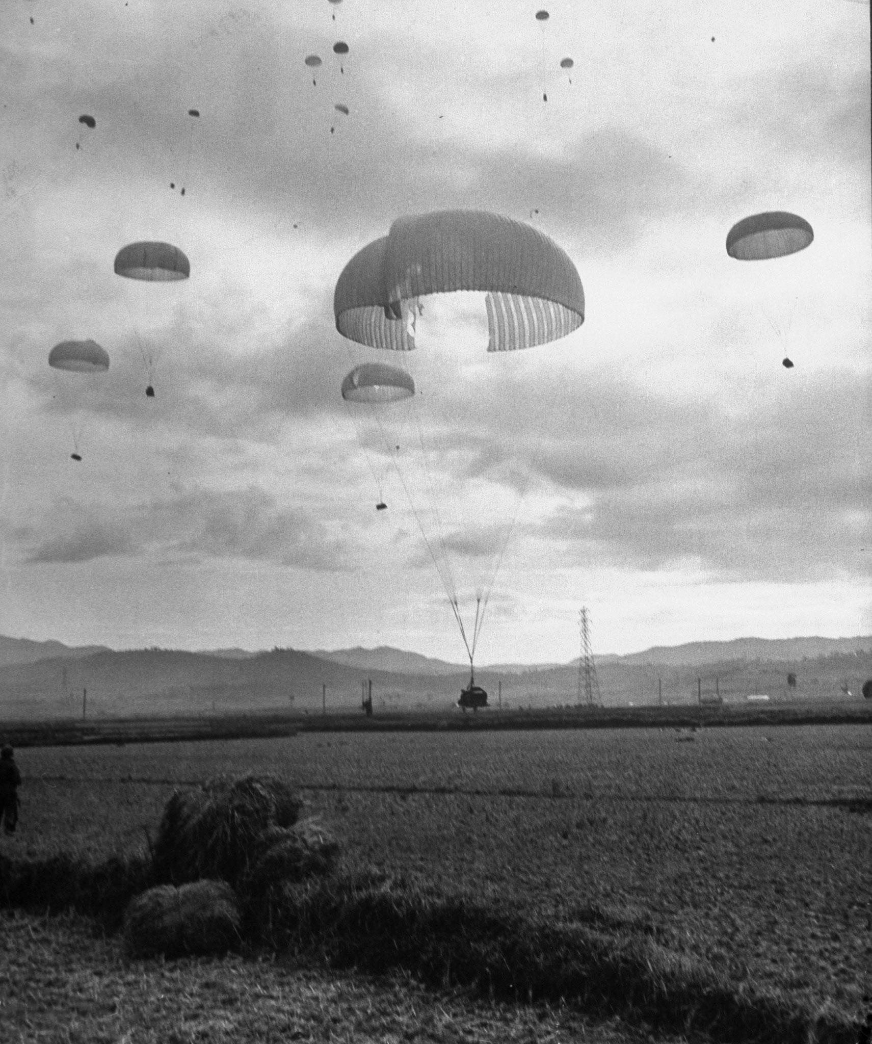 American paratroopers landing in Korea, with one ripped chute still holding enough air to drop safely, 1950.