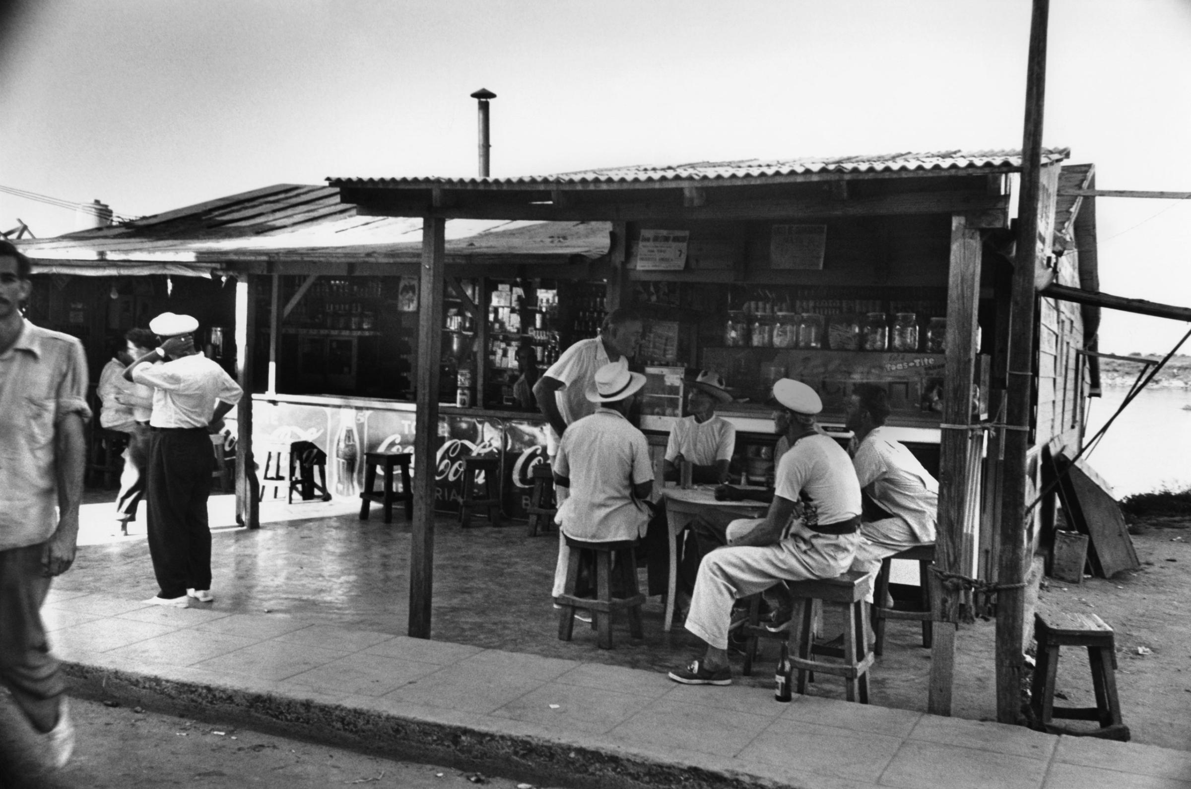 Ernest Hemingway chats with fellow patrons at a cafe he enjoyed frequenting in Cuba, 1952.