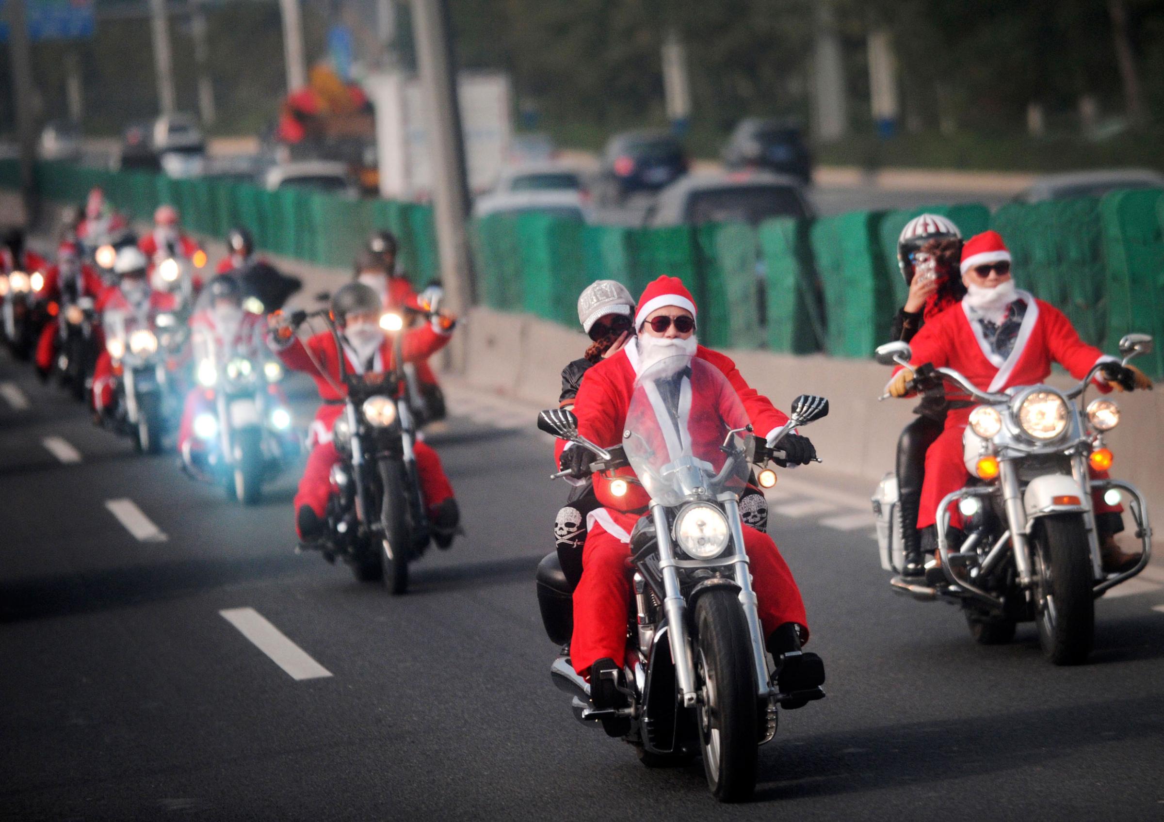 Owners of Harley-Davidson motorcycles wearing Santa Claus costumes ride along a street to give presents to elders at a nursing home during a promotional event celebrating Christmas in Guangzhou, Guangdong province on Dec. 24, 2014.