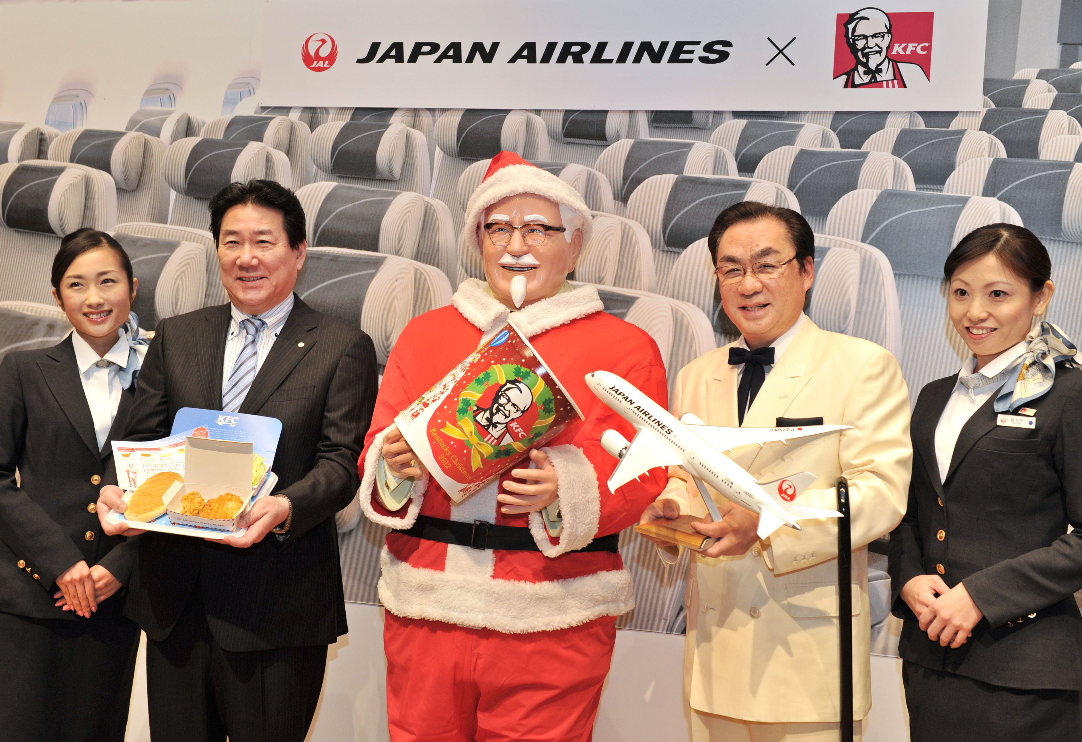 Japan Airlines President Yoshiharu Ueki (2nd L) and Masao Watanabe (2nd R), President of Kentucky Fried Chicken Japan pose with a statue of Colonel Sanders (C) wearing a Santa Claus costume during a photo session after a press conference to announce their new "AIR Kentucky Fried Chicken" in-flight fried chicken service, in Tokyo on November 28, 2012. (KAZUHIRO NOGI—AFP/Getty Images)