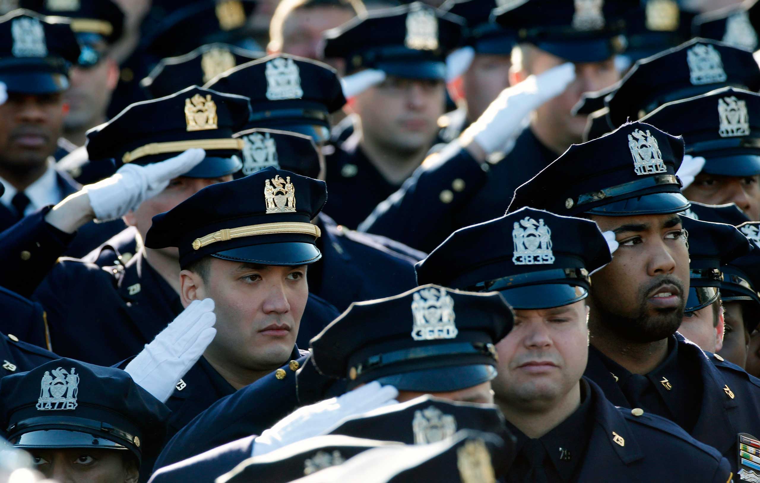 Police salute during the playing of the U.S. National Anthem outside the Christ Tabernacle Church at the start of the funeral service for slain New York Police Department (NYPD) officer Rafael Ramos in the Queens borough of New York Dec. 27, 2014. (Mike Segar—Reuters)