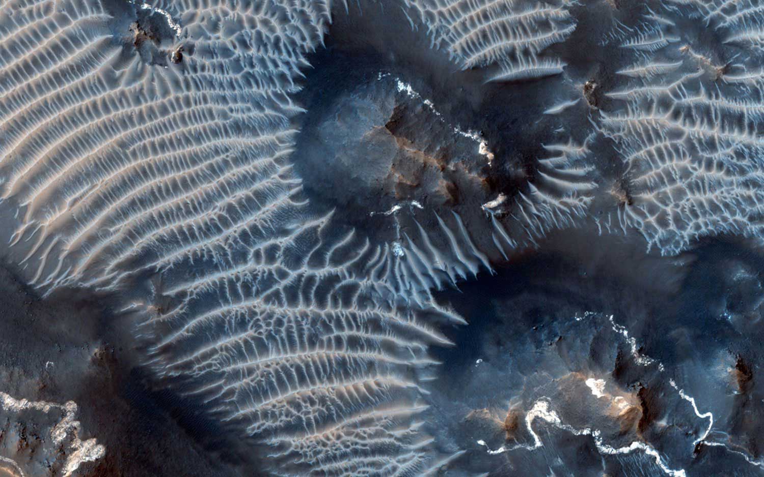 The Noctis Labyrinthus region of Mars, perched high in the Valles Marineris canyon system, as seen on Sept. 26, 2013. The image shows bright rimmed bedrock knobs, as well as two types of windblown sediments.