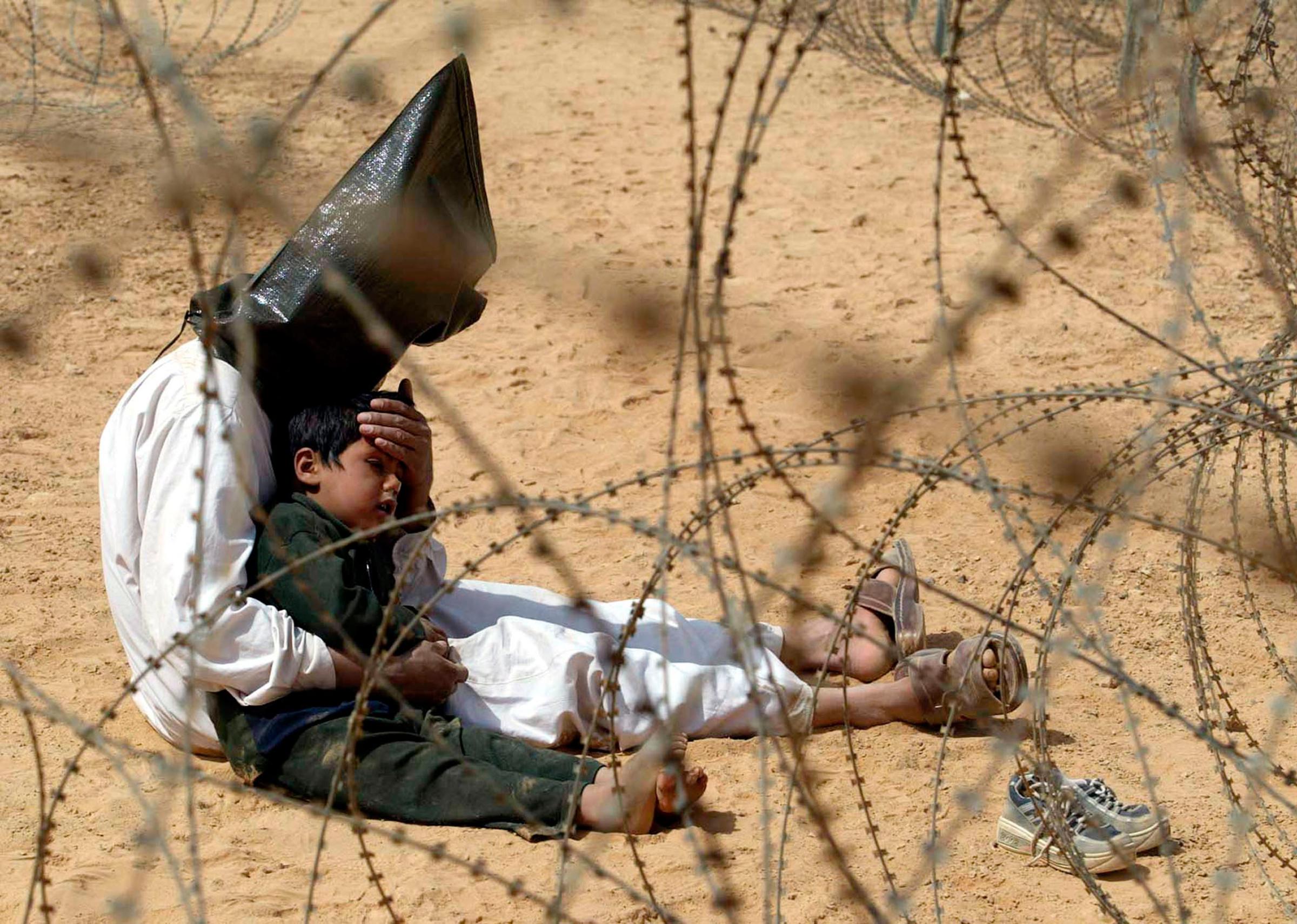 An Iraqi prisoner of war comforts his 4-year-old son at a regroupment center for POWs of the 101st Airborne Division near An Najaf on March 31, 2003.