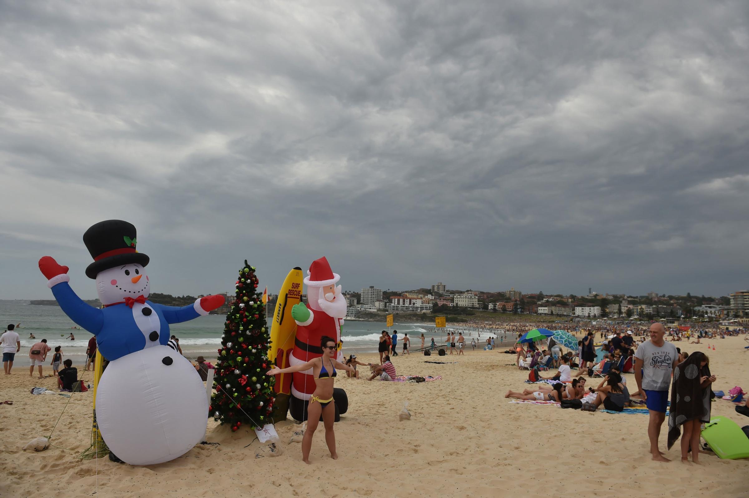Visitors take photos in front of an inflatable snow man and Santa Claus on Bondi Beach on Christmas Day on Dec. 25, 2014.