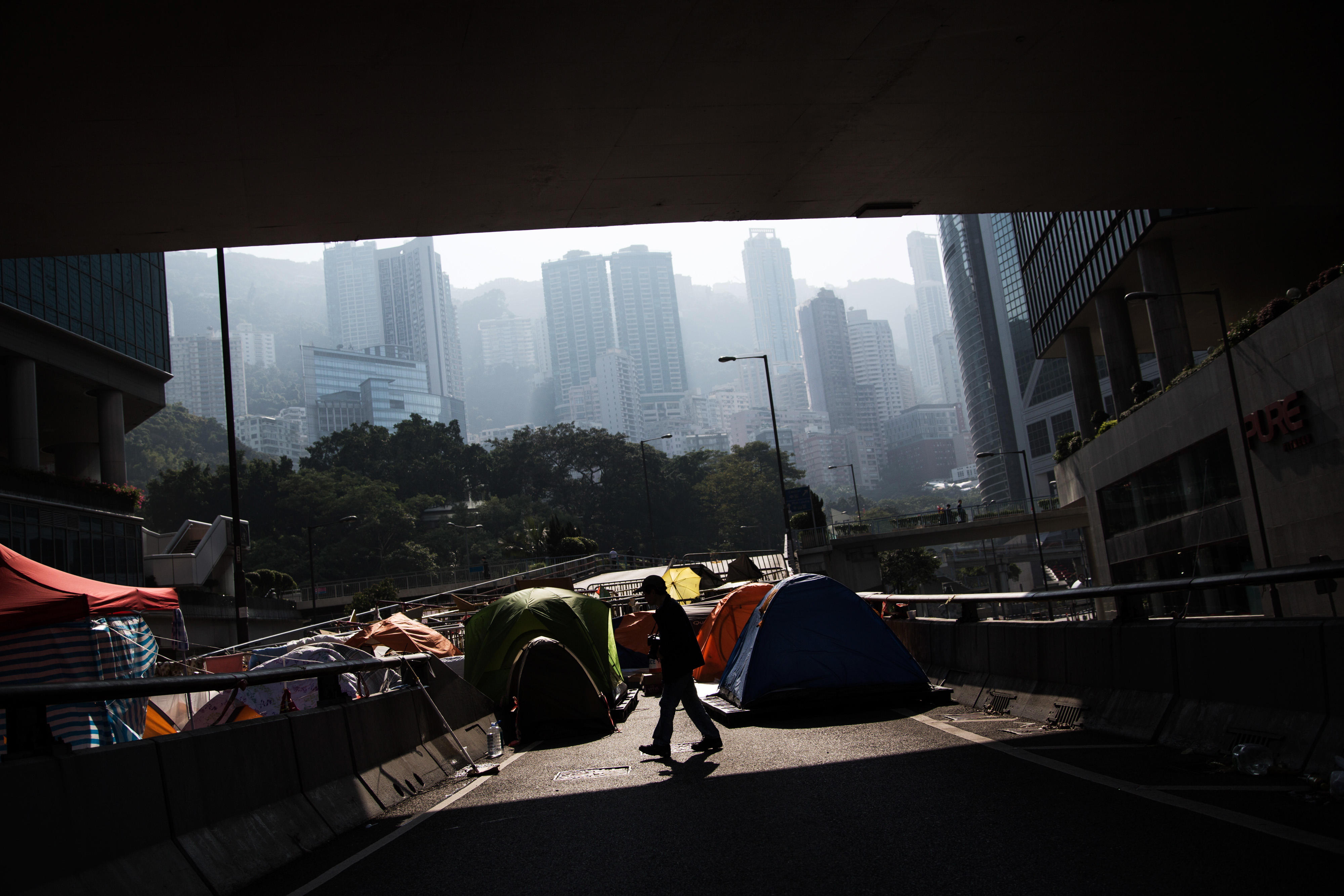 A man is silhouetted walking past tents on a flyover in the Admiralty district of Hong Kong on Dec. 9, 2014. Pro-democracy demonstrators in Hong Kong are bracing for police to clear part of their main protest site in two days following a court order to reopen roads that have been occupied for more than two months (Bloomberg/Getty Images)