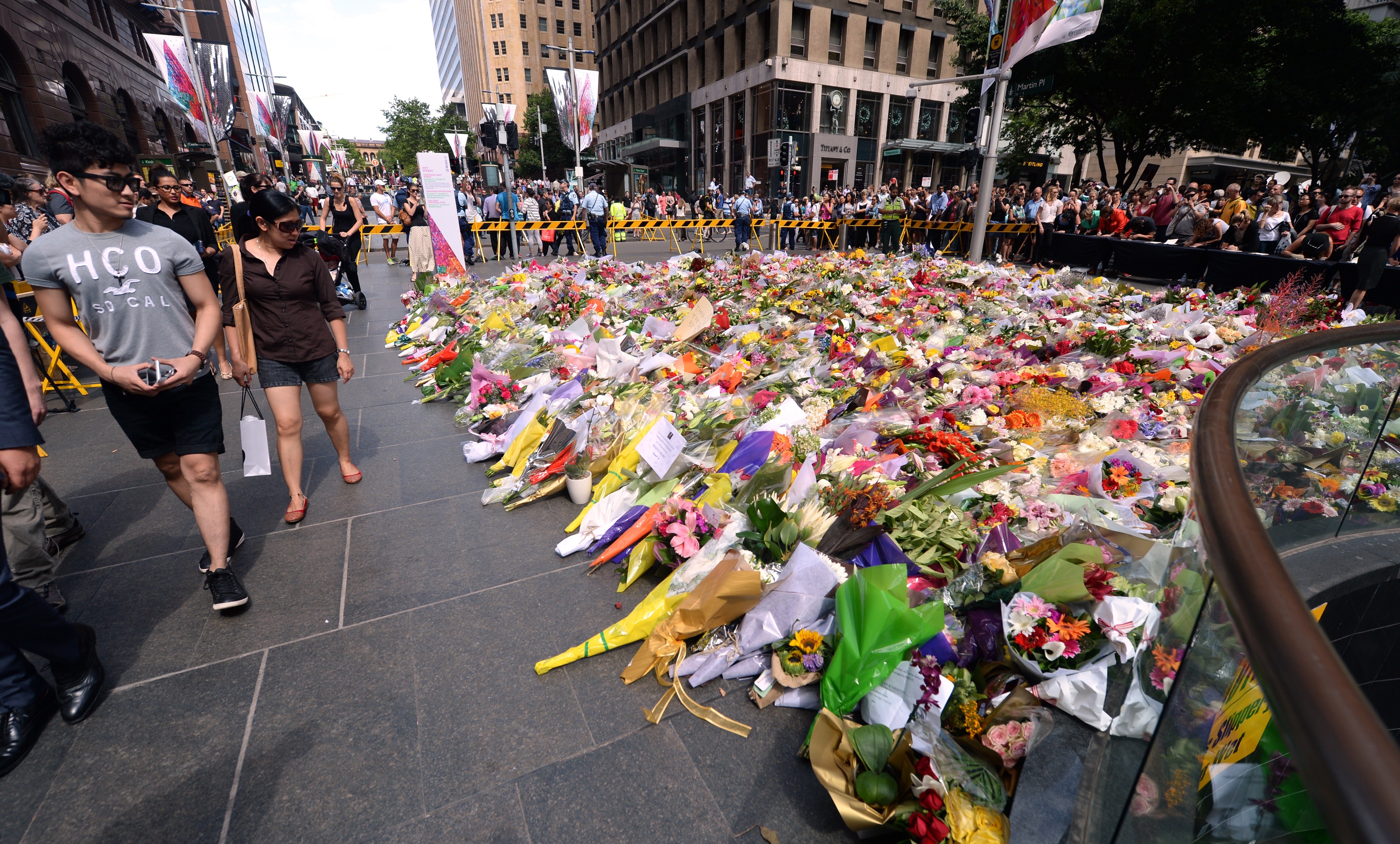 Visitors look at a makeshift memorial near the scene of the fatal siege in the heart of Sydney's financial district on Dec. 16, 2014. Sydneysiders including tearful office workers and Muslim women in hijabs laid flowers at the scene in an outpouring of grief and shock (Peter Parks—AFP/Getty Images)