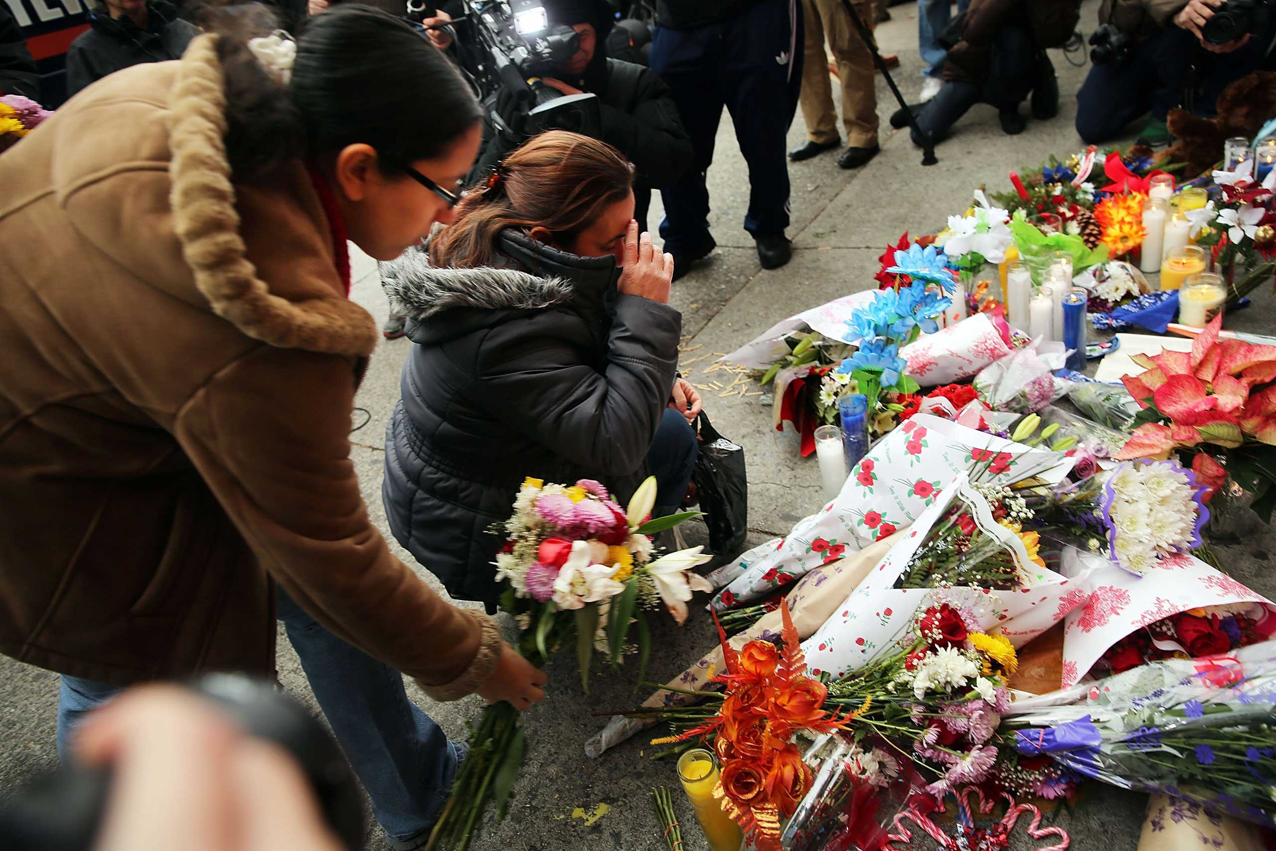 Women place flowers at a memorial to the two New York Police Department (NYPD) officers that were shot and killed nearby Dec. 21, 2014 in the Bedford Stuyvesant neighborhood of the Brooklyn borough of New York City. (Spencer Platt—Getty Images)