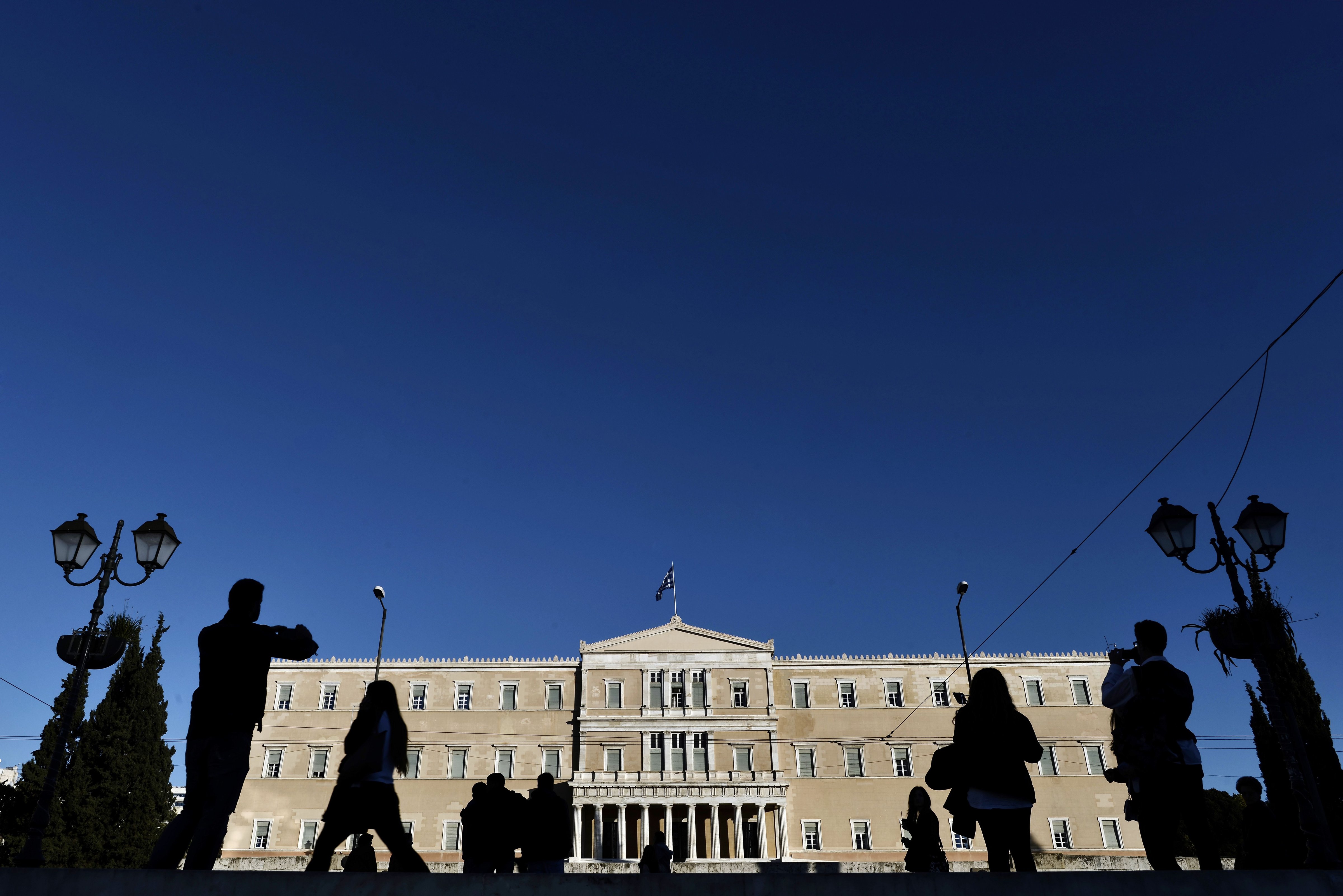 People walk past the Greek Parliament in Athens on Dec. 17, 2014. Greece is a step away from early elections that could repudiate its international bailout and rekindle a euro-zone crisis after lawmakers failed to elect a President (Aris Messinis—AFP/Getty Images)
