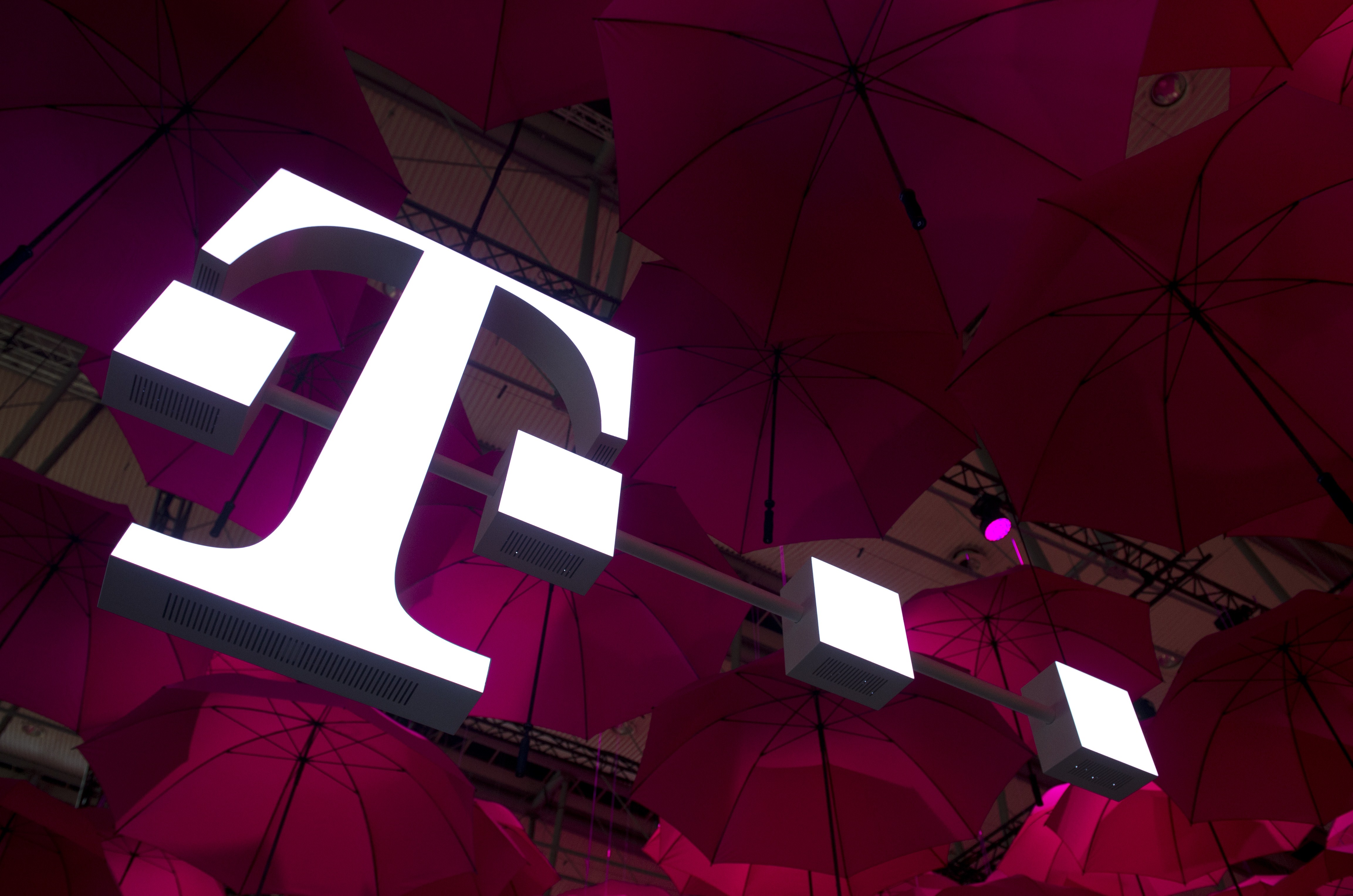 A Deutsche Telekom T-Mobile logo hangs under pink umbrellas at the stand of the German telecommunications giant at the 2014 CeBIT computer technology trade fair on March 10, 2014 in Hanover, central Germany. (John Macdougall&mdash;AFP/Getty Images)