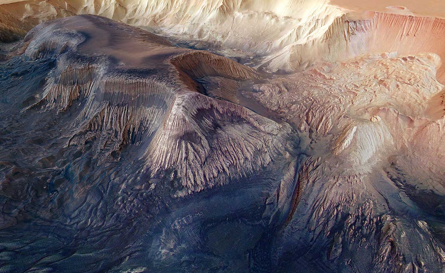 A flat-topped mesa is located in the center of Hebes Chasma on Mars and rises to a similar height as the surrounding plains. Exposed within the walls of the mesa are layers of sediments deposited by wind and water. Numerous grooves are etched into the mountain, suggesting the material is weak and easily eroded.