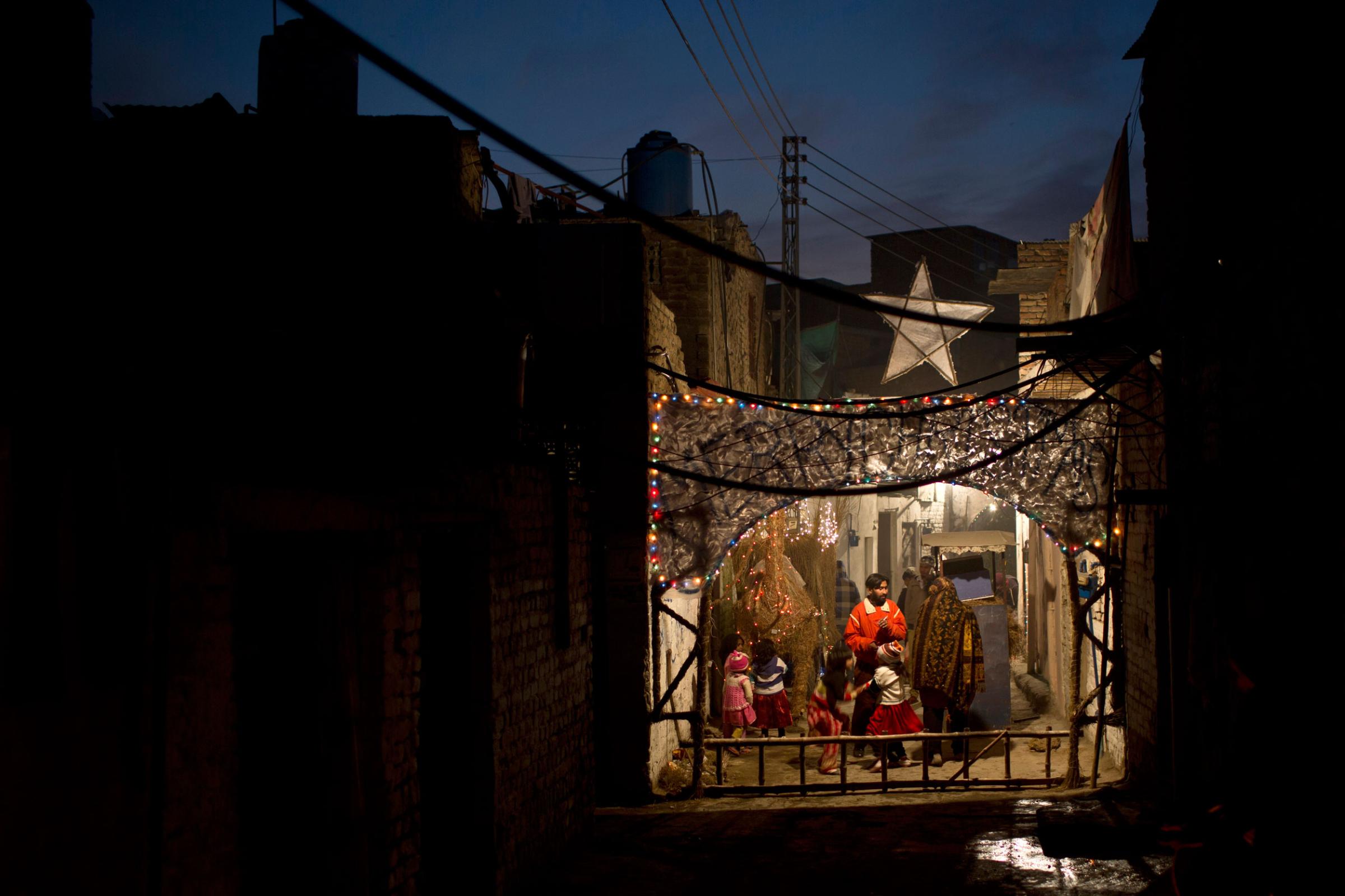 Pakistani Christians gather in an alley of a Christian neighborhood decorated with festive lights for Christmas in Islamabad, Pakistan on Dec. 24, 2014.