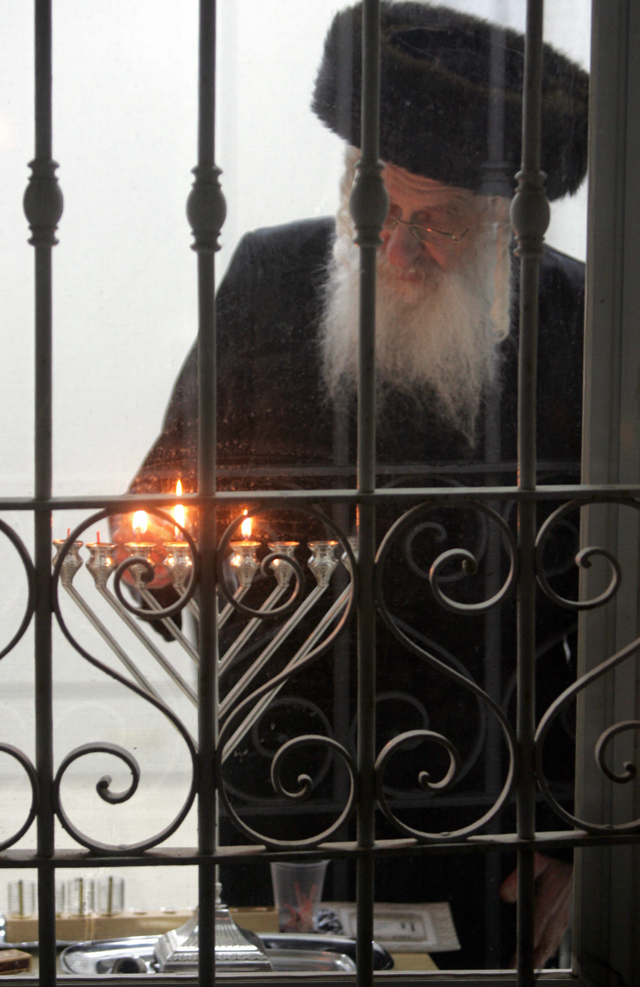 An Ultra-Orthodox Jewish man lights the candles of the fifth night of the Jewish holiday of Hanukah, in the ultra-Orthodox neighborhood of Mea Shearim in Jerusalem. (MENAHEM KAHANA—AFP/Getty Images)