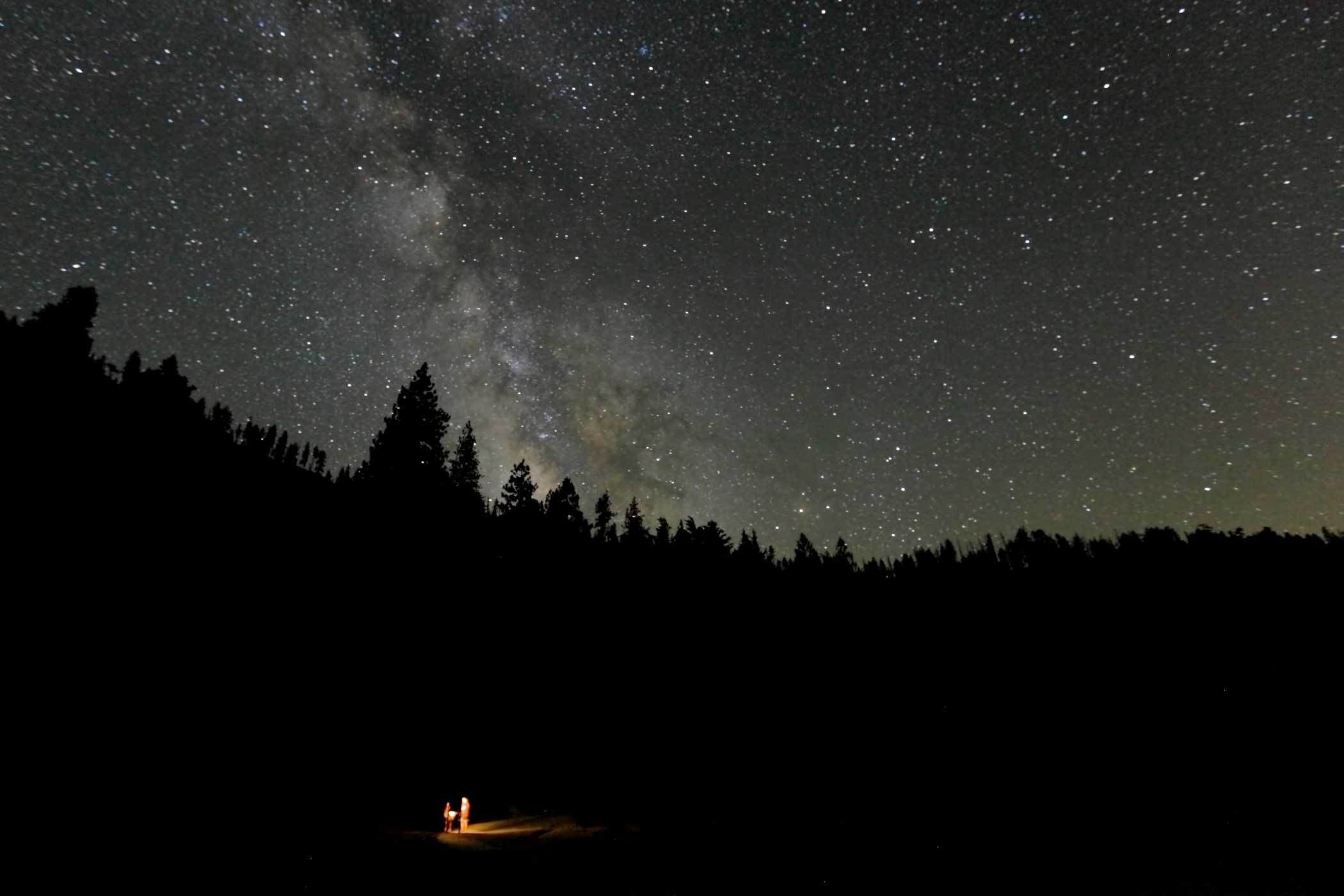 The photographer came across two hikers lost in the wilderness of Yosemite late one evening in July 2011. He captured this image of the tiny figures in a small bubble of torchlight set within a vast, pitch black forest beneath the immense dome of the sky. It highlights the wonder, beauty and awe of astronomy.